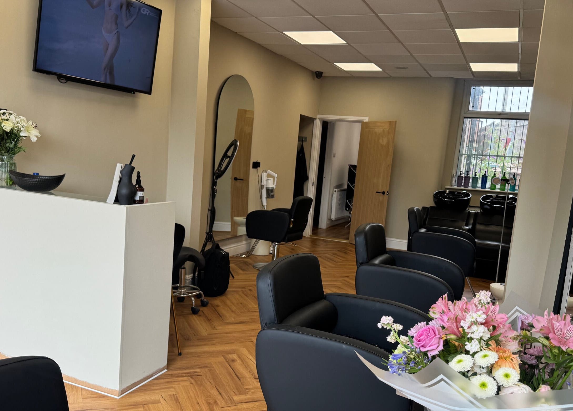 Modern salon interior at STYLED | By Melissa, Reddish, England, GB featuring sleek chairs and vibrant flowers.
