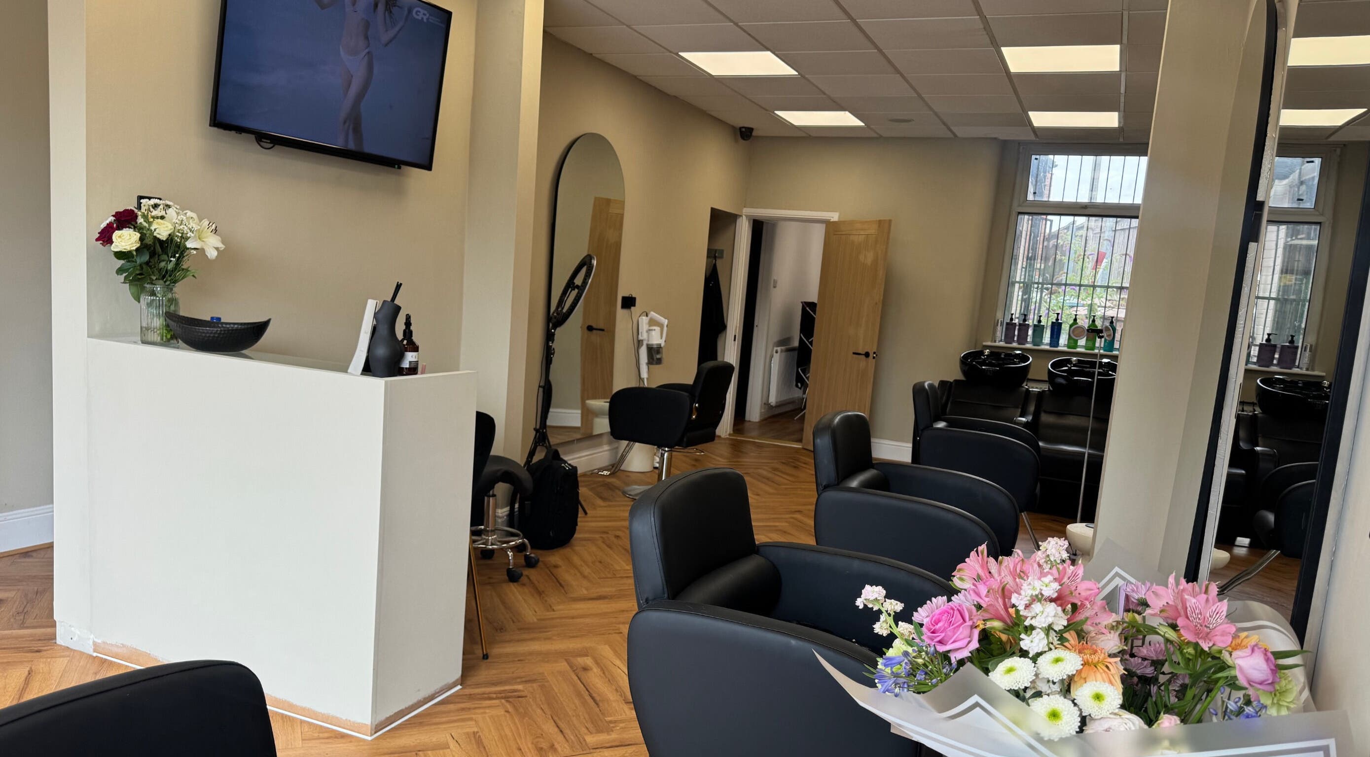 Modern salon interior at STYLED | By Melissa, Reddish, England, GB featuring sleek chairs and vibrant flowers.