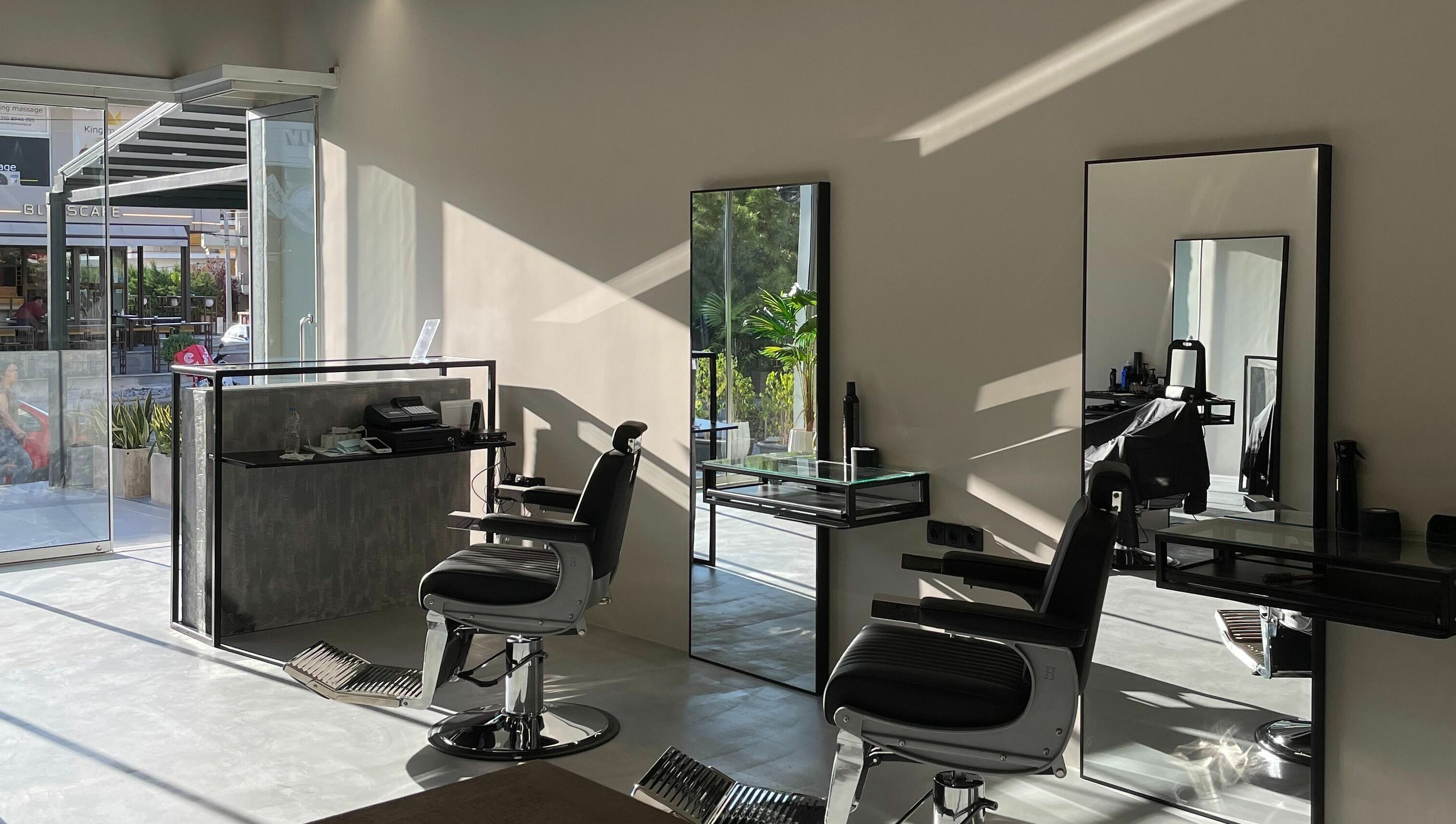 Modern salon interior at GROOMING CO. in ATHENS, GR with sleek chairs and mirrors.