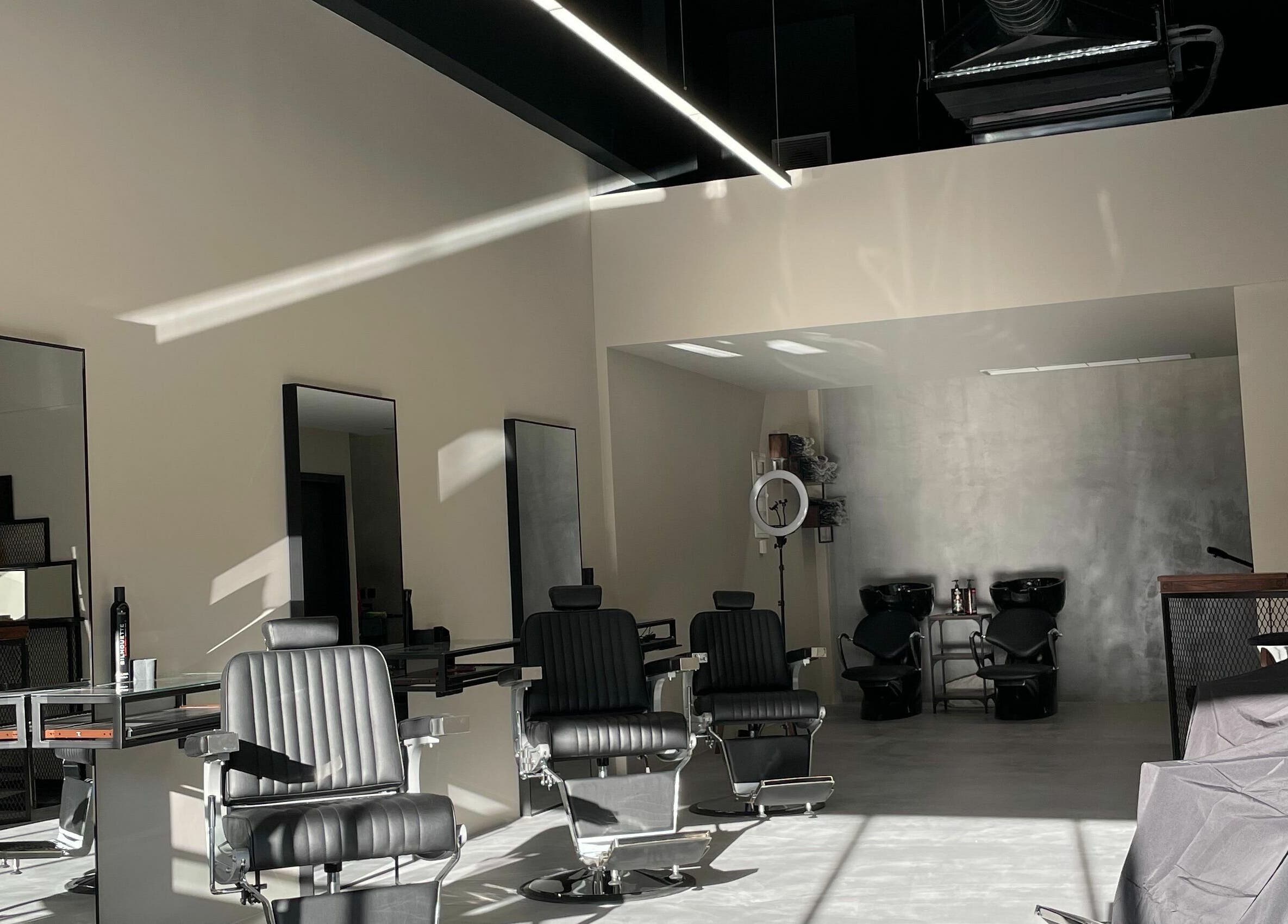 Modern interior of GROOMING CO. in Athens, GR with sleek black barber chairs and mirrors.