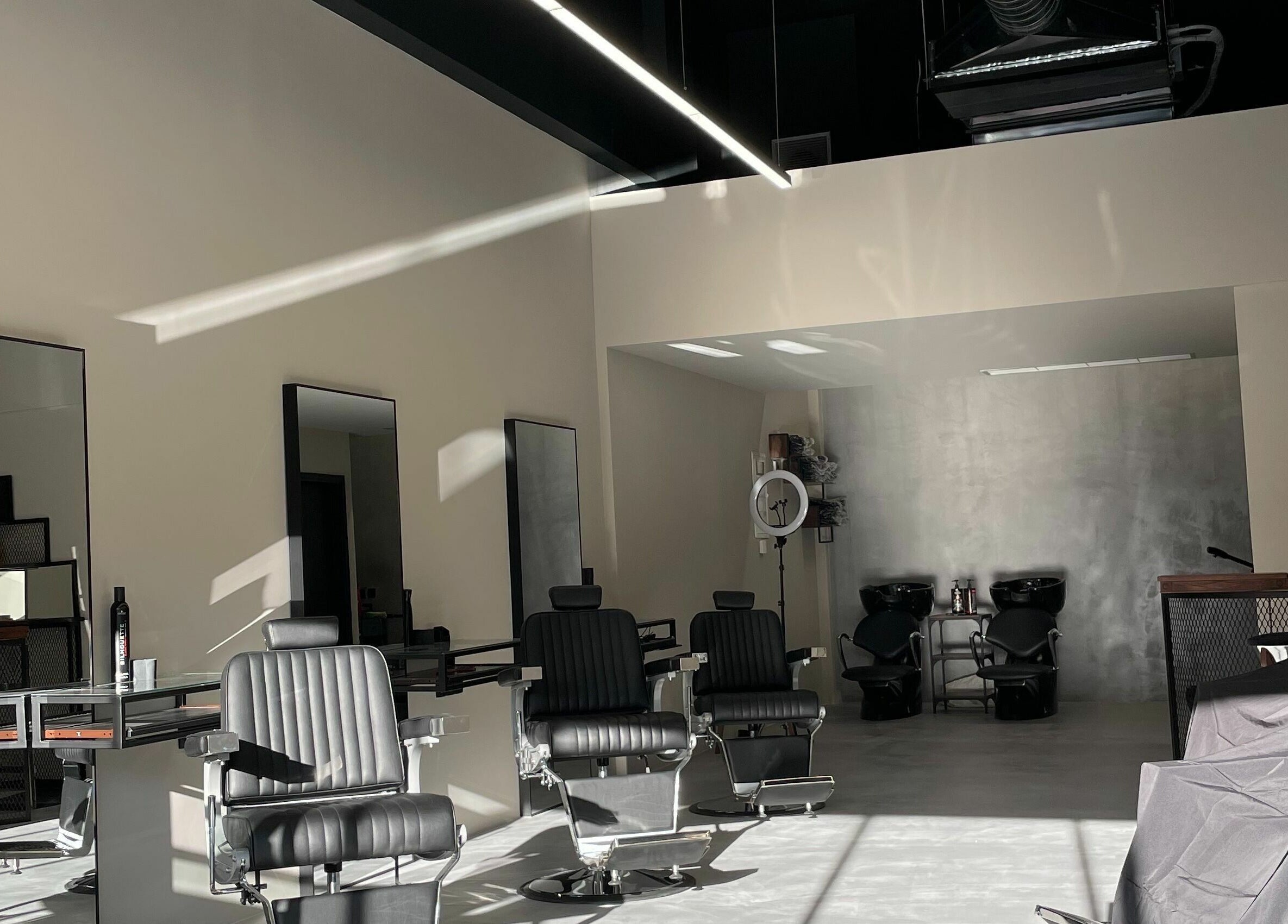 Modern interior of GROOMING CO. in Athens, GR with sleek black barber chairs and mirrors.