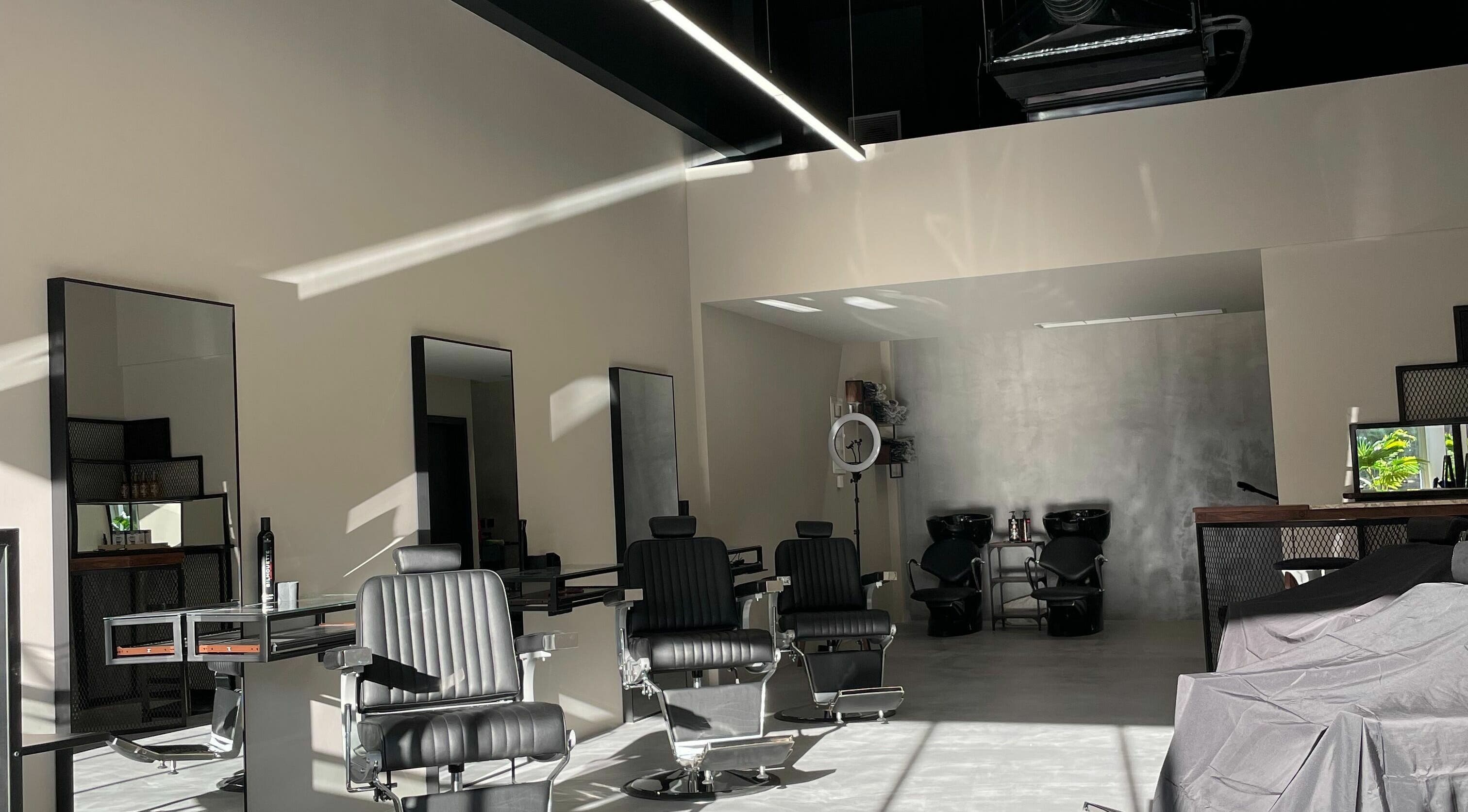 Modern interior of GROOMING CO. in Athens, GR with sleek black barber chairs and mirrors.