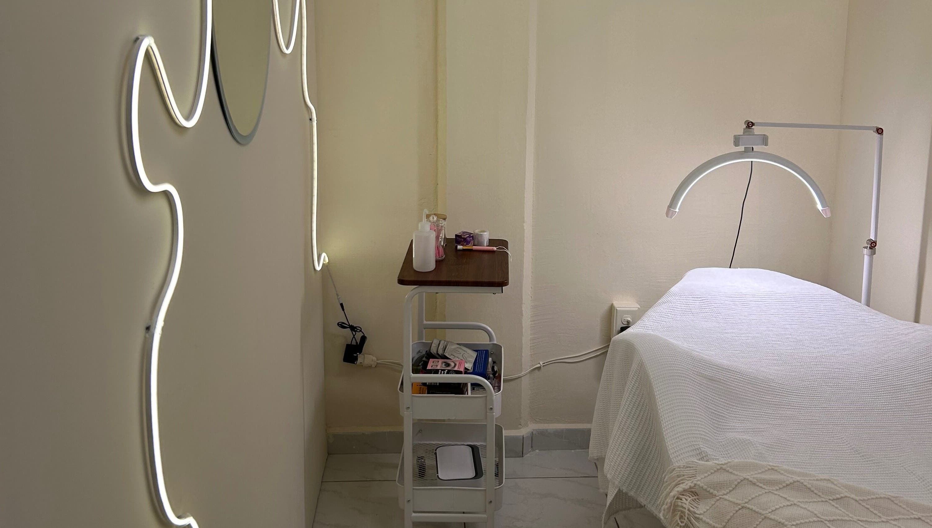 Sala de tratamiento en LEIA, Juriquilla, Querétaro, MX con iluminación moderna y camilla acogedora.