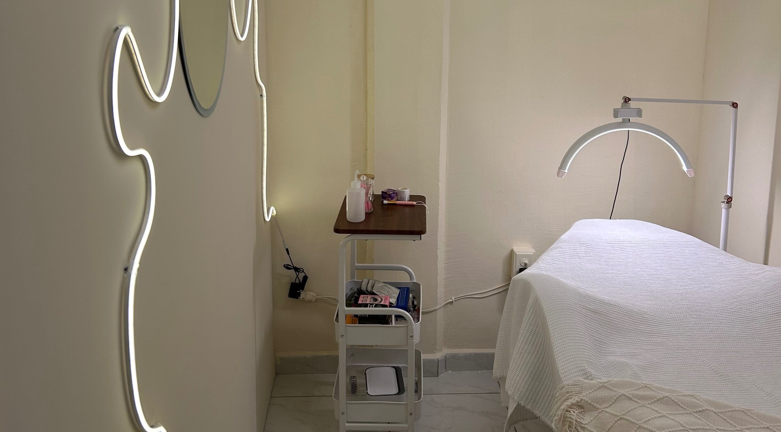 Sala de tratamiento en LEIA, Juriquilla, Querétaro, MX con iluminación moderna y camilla acogedora.