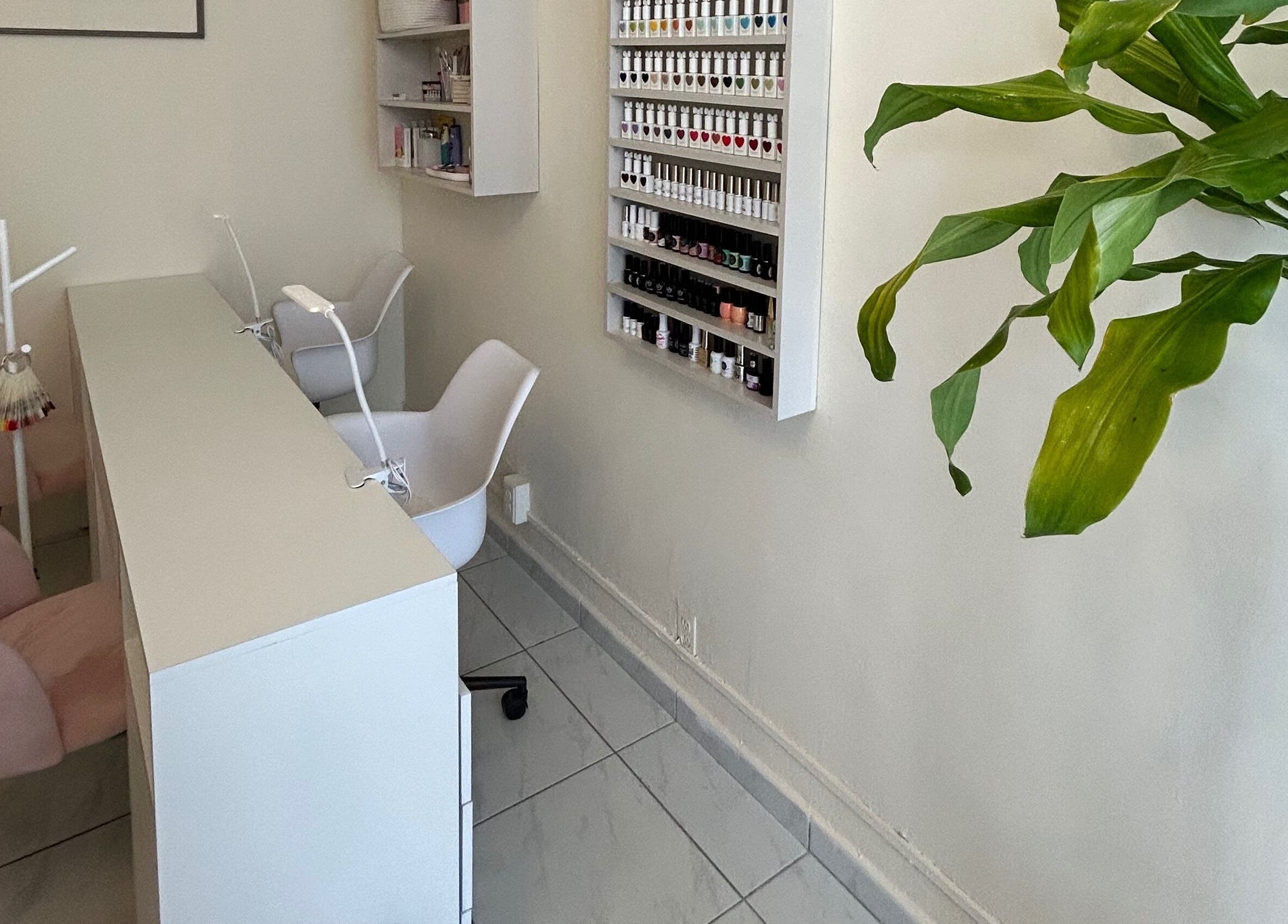 Espacio de manicura en LEIA, Juriquilla, Querétaro, MX. Mesa blanca, sillas rosadas y estantes de esmaltes.