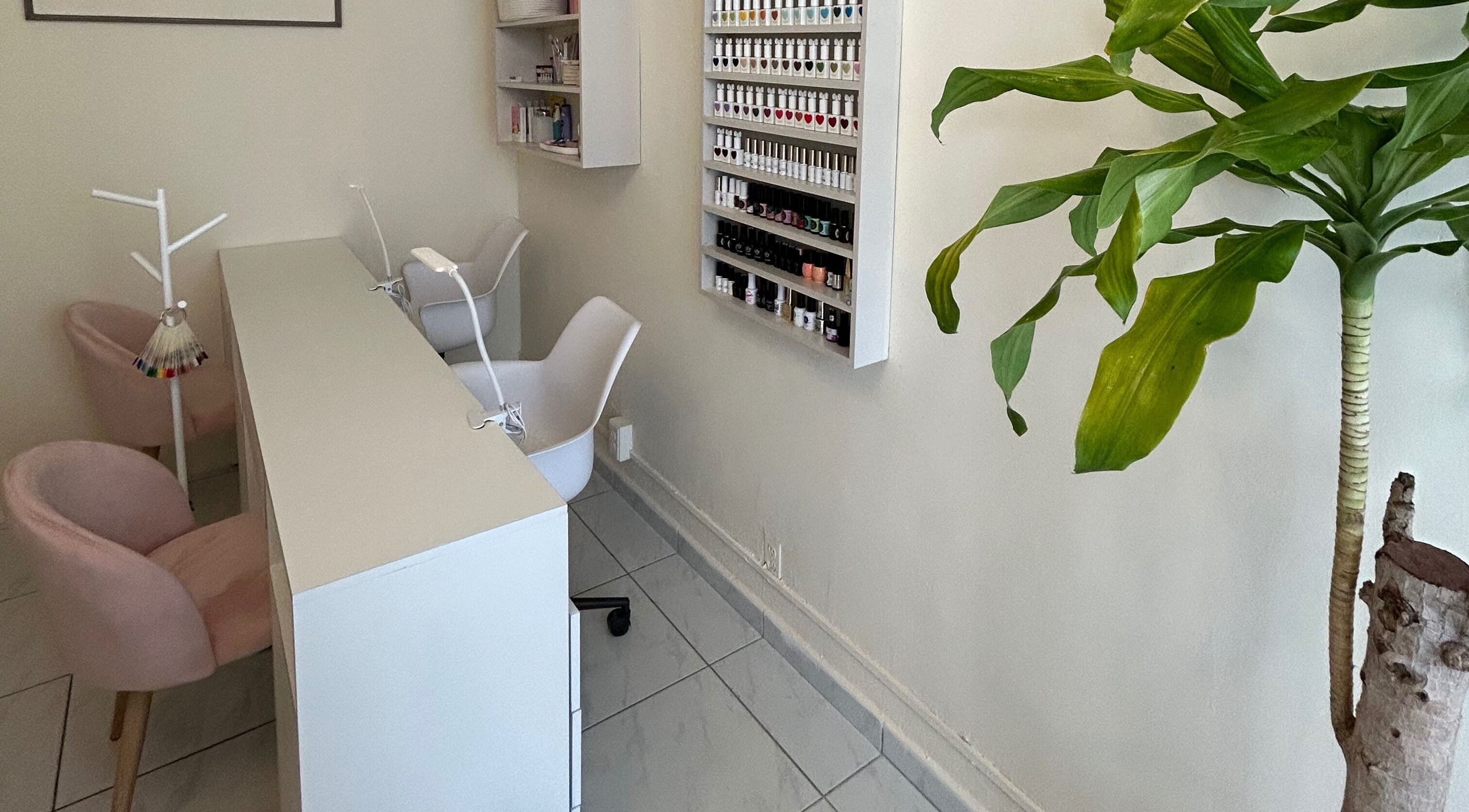 Espacio de manicura en LEIA, Juriquilla, Querétaro, MX. Mesa blanca, sillas rosadas y estantes de esmaltes.