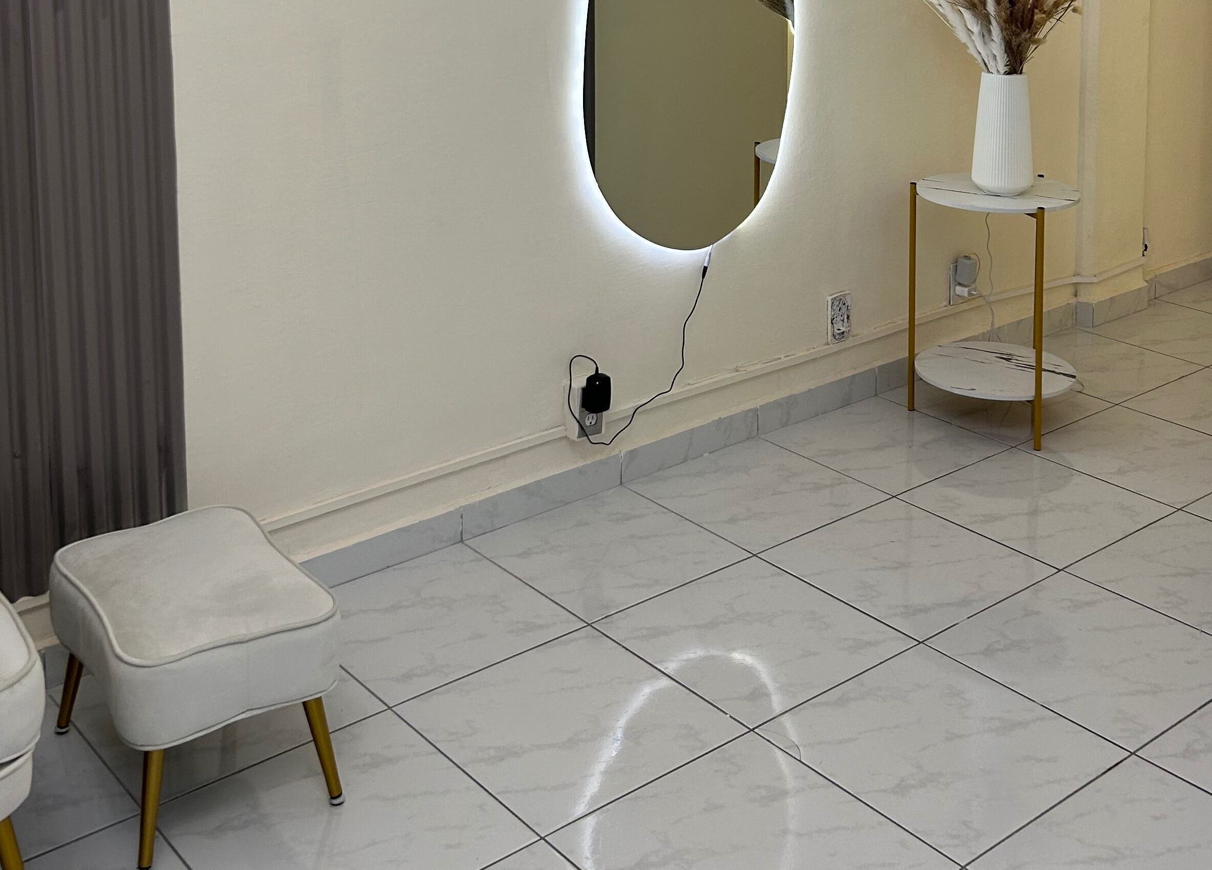 Espacio acogedor en LEIA, Juriquilla, Querétaro, MX con silla blanca, espejo iluminado y decoración minimalista.