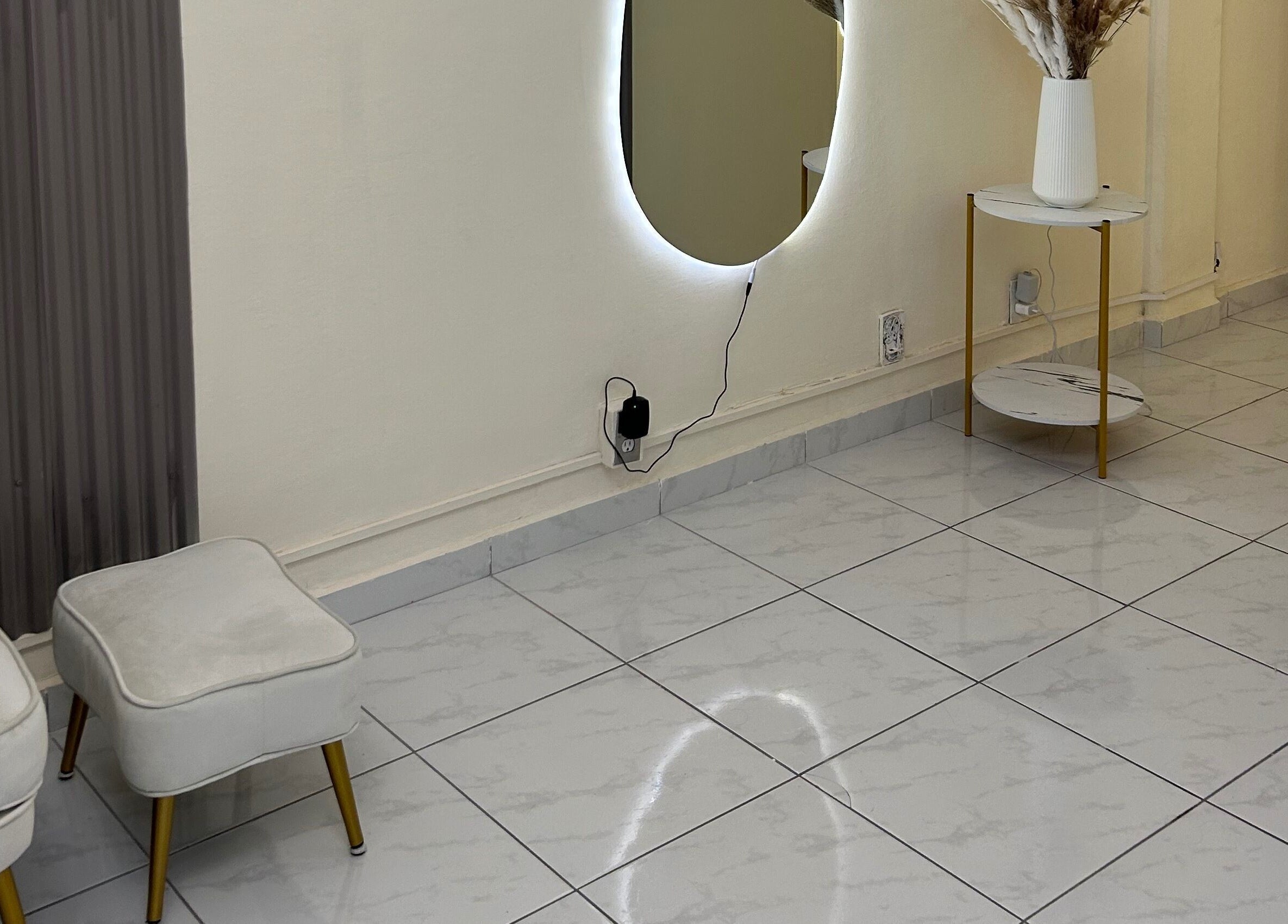 Espacio acogedor en LEIA, Juriquilla, Querétaro, MX con silla blanca, espejo iluminado y decoración minimalista.