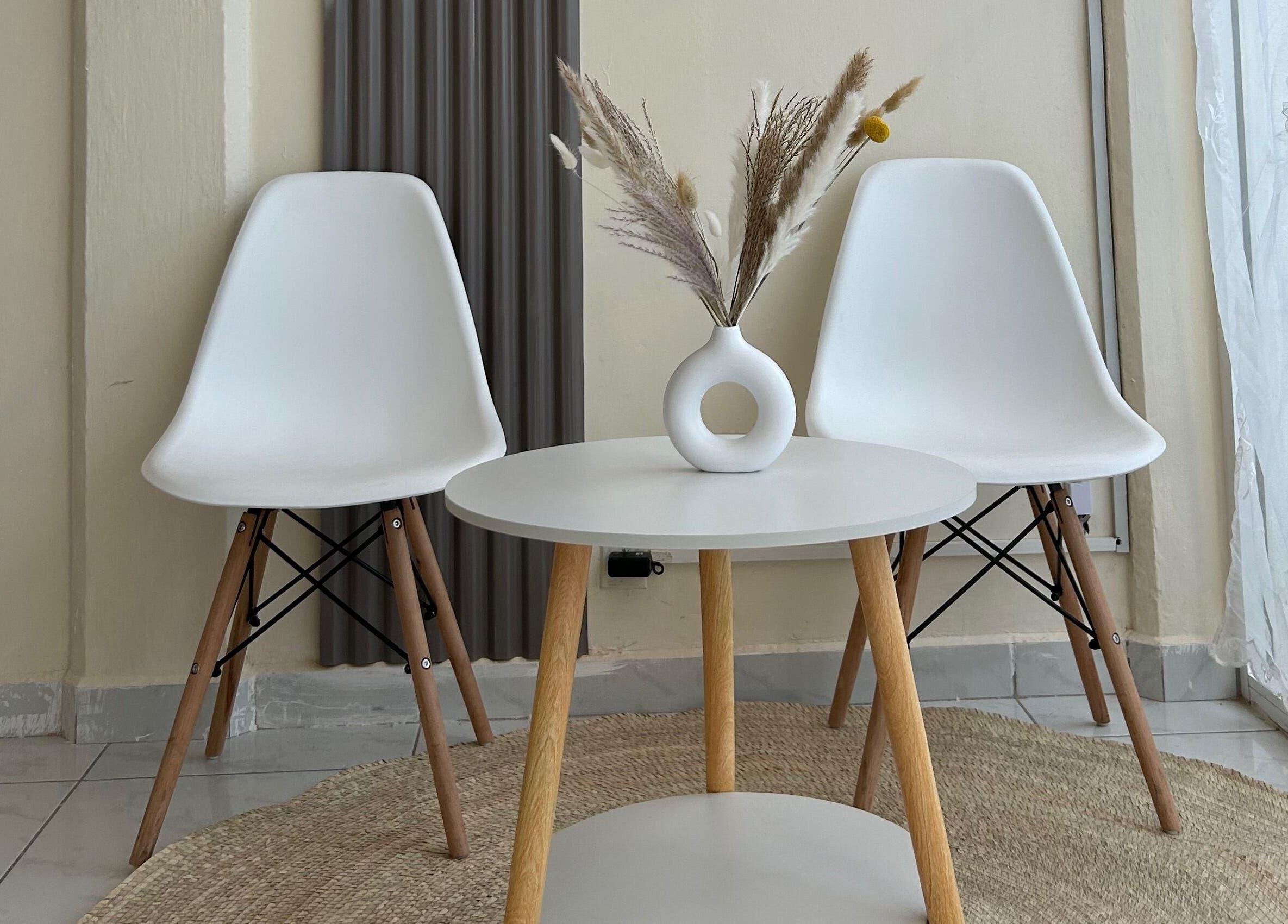 Sala de espera minimalista en LEIA, Juriquilla, Querétaro, MX con sillas blancas y mesa decorativa.