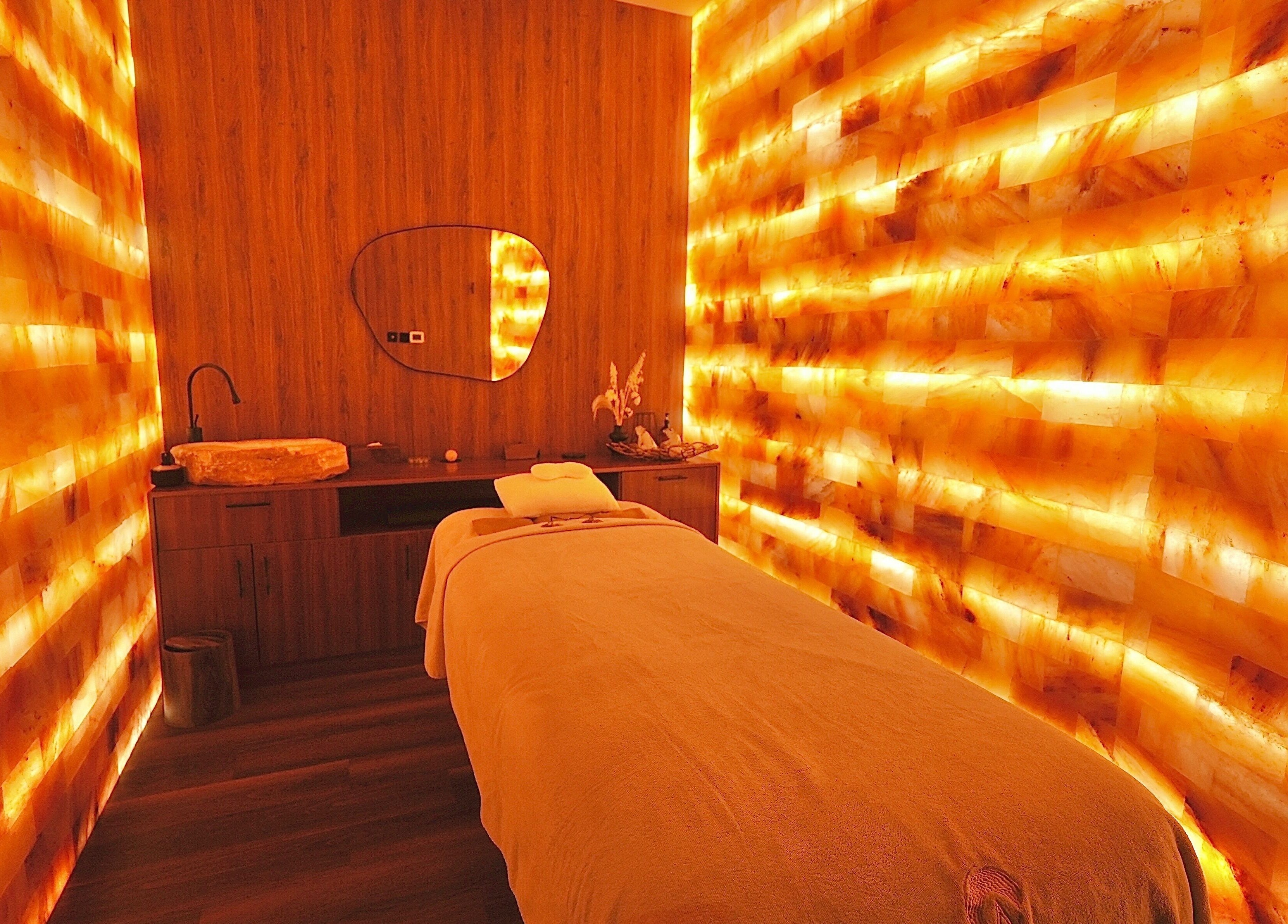 Warm-lit therapy room at Adara Spa Retreat, Ladies Spa, Dubai, Dubai, AE with salt walls and massage bed.