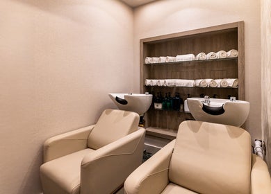 Elegant salon wash station at George Vallossian, London, England, GB with plush chairs and rolled towels.