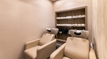 Elegant salon wash station at George Vallossian, London, England, GB with plush chairs and rolled towels.