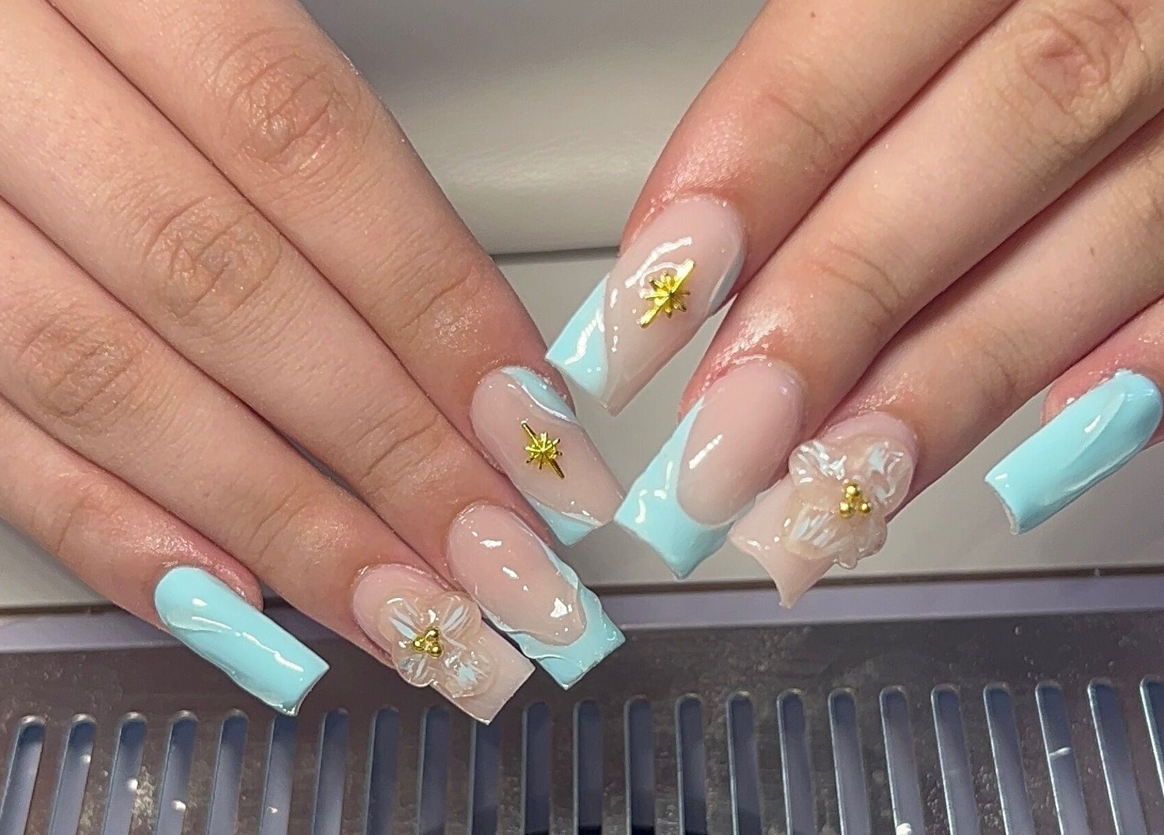 Intricate floral nail art at Beauty By Hannah in Moorside, England, GB, showcasing elegant blue and gold details.