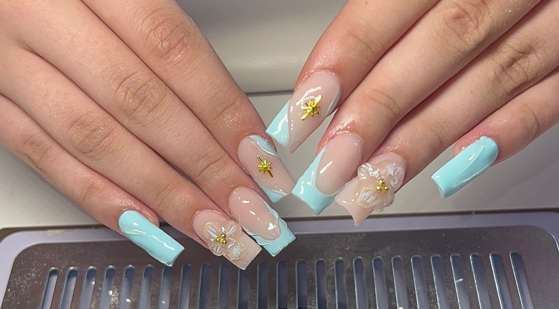 Intricate floral nail art at Beauty By Hannah in Moorside, England, GB, showcasing elegant blue and gold details.