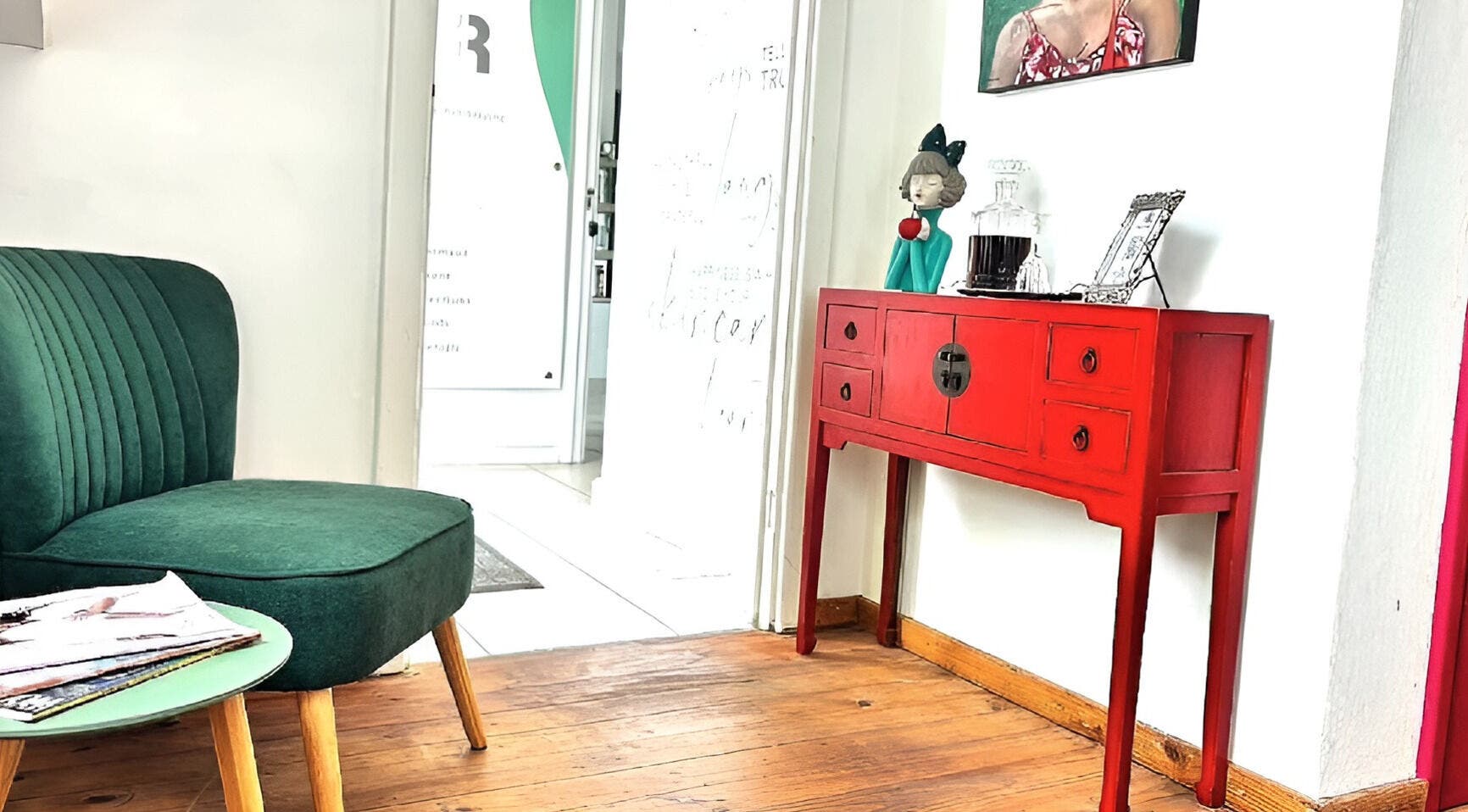 Cozy seating area at Rum and Ruby Hair Design, Hermanus, Western Cape, ZA with green chair and red console.