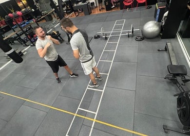 Two men boxing in ELK - Novo fitness center, Brest, Bretagne, FR, filled with gym equipment.
