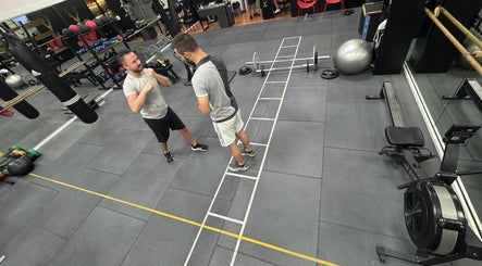Two men boxing in ELK - Novo fitness center, Brest, Bretagne, FR, filled with gym equipment.