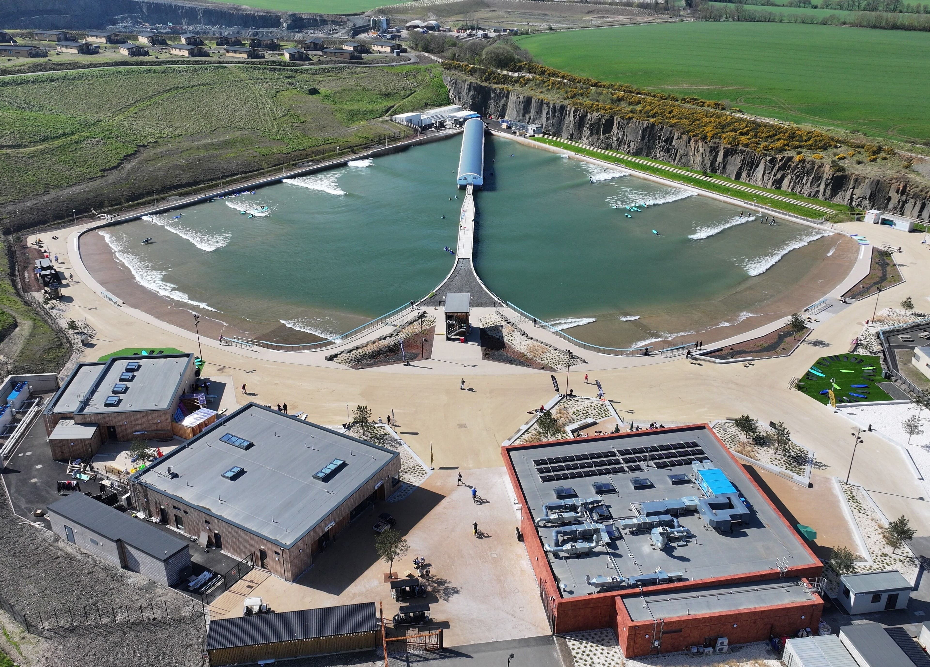 Aerial view of Spa Studio by Lost Shore in Newbridge, Scotland, GB showing a serene lagoon and modern facilities.