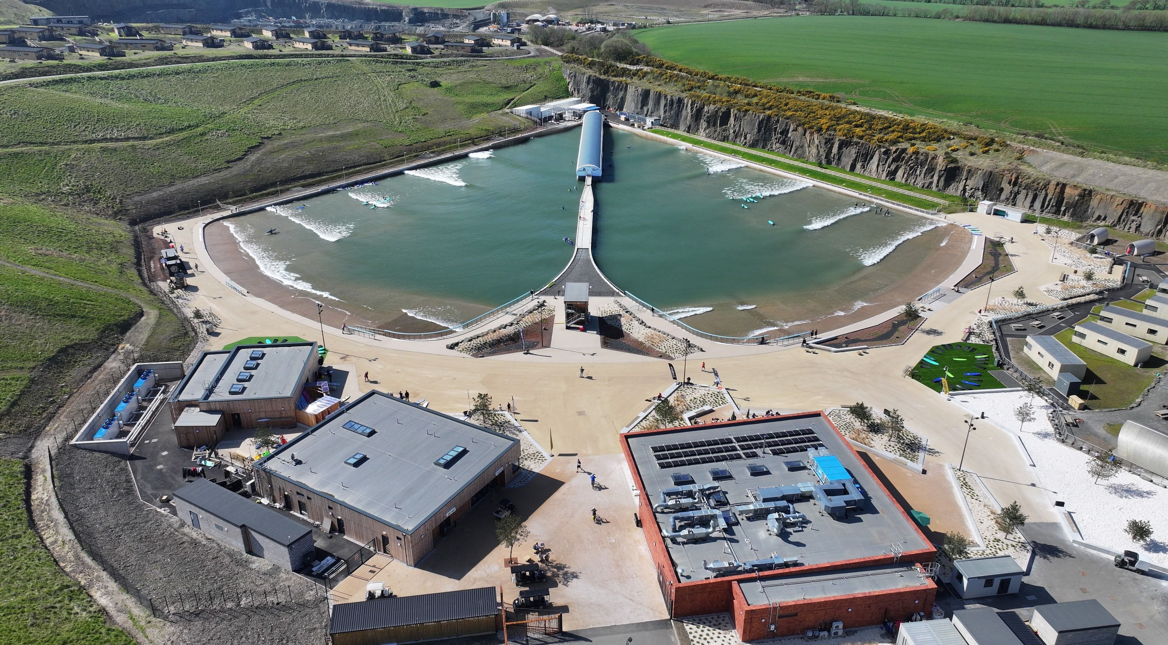 Aerial view of Spa Studio by Lost Shore in Newbridge, Scotland, GB showing a serene lagoon and modern facilities.