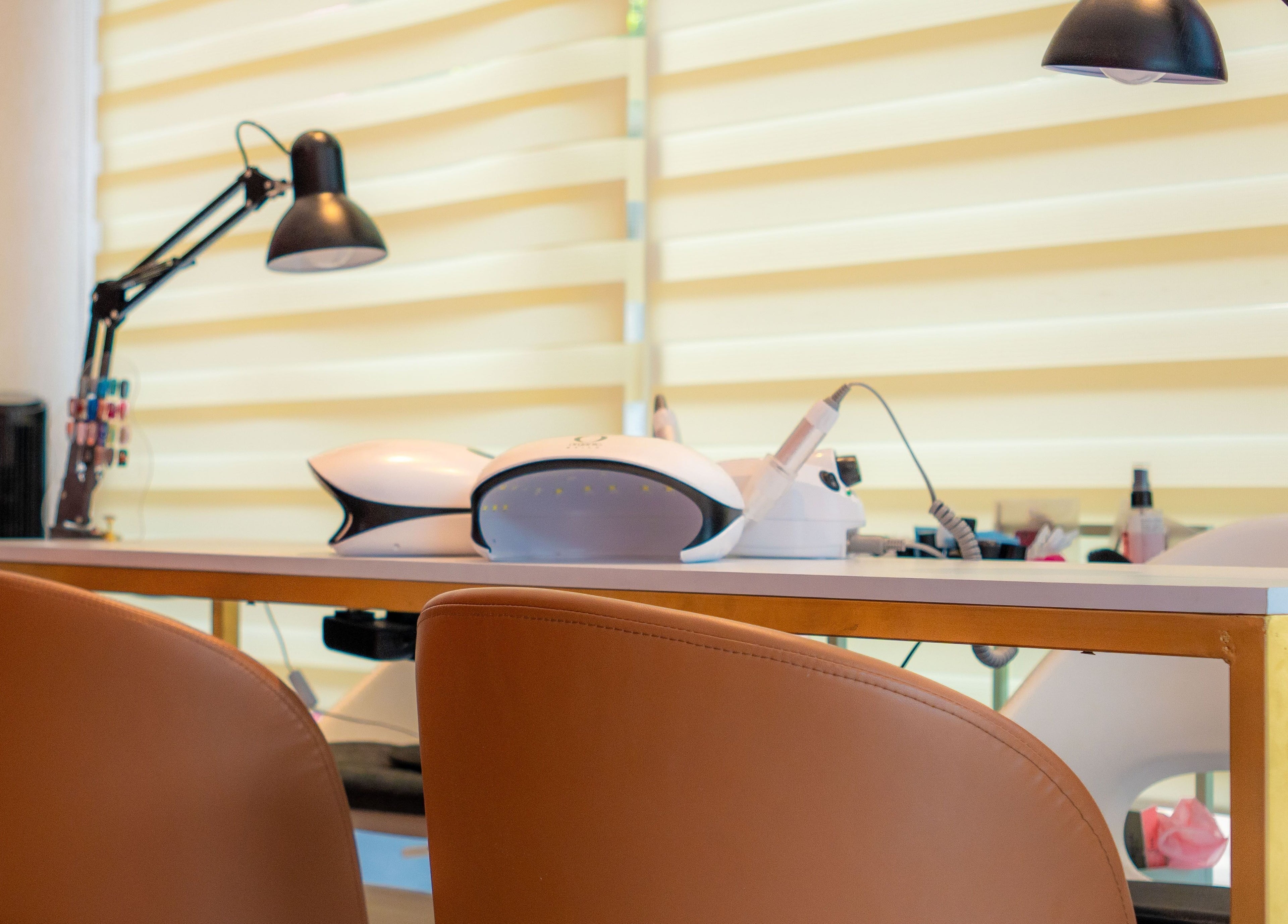 Mesa de manicura en Bloom! Estudio de uñas, Ciudad De México, MX, equipada con modernas lámparas y herramientas.