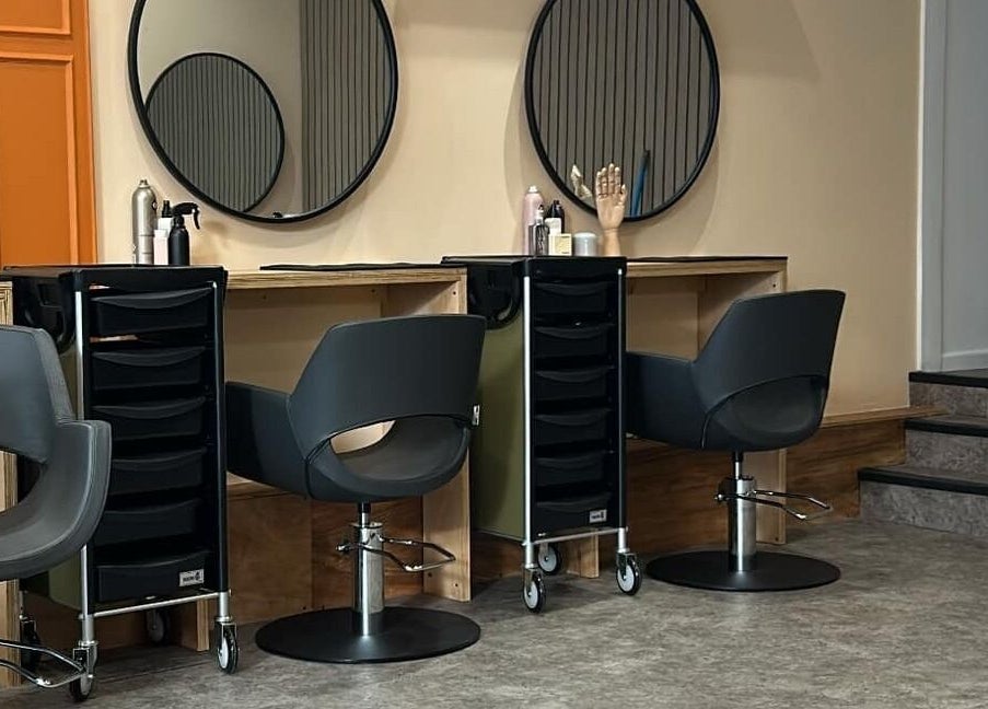 Modern salon station at Peach 37, Exeter, England, GB with sleek chairs and large round mirrors.