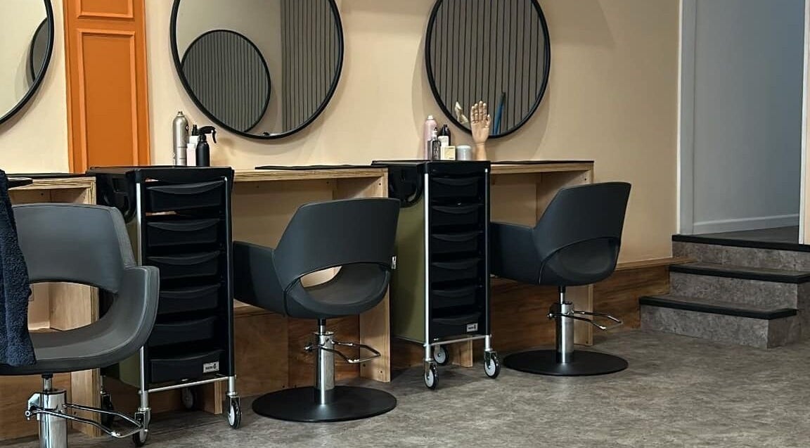 Modern salon station at Peach 37, Exeter, England, GB with sleek chairs and large round mirrors.