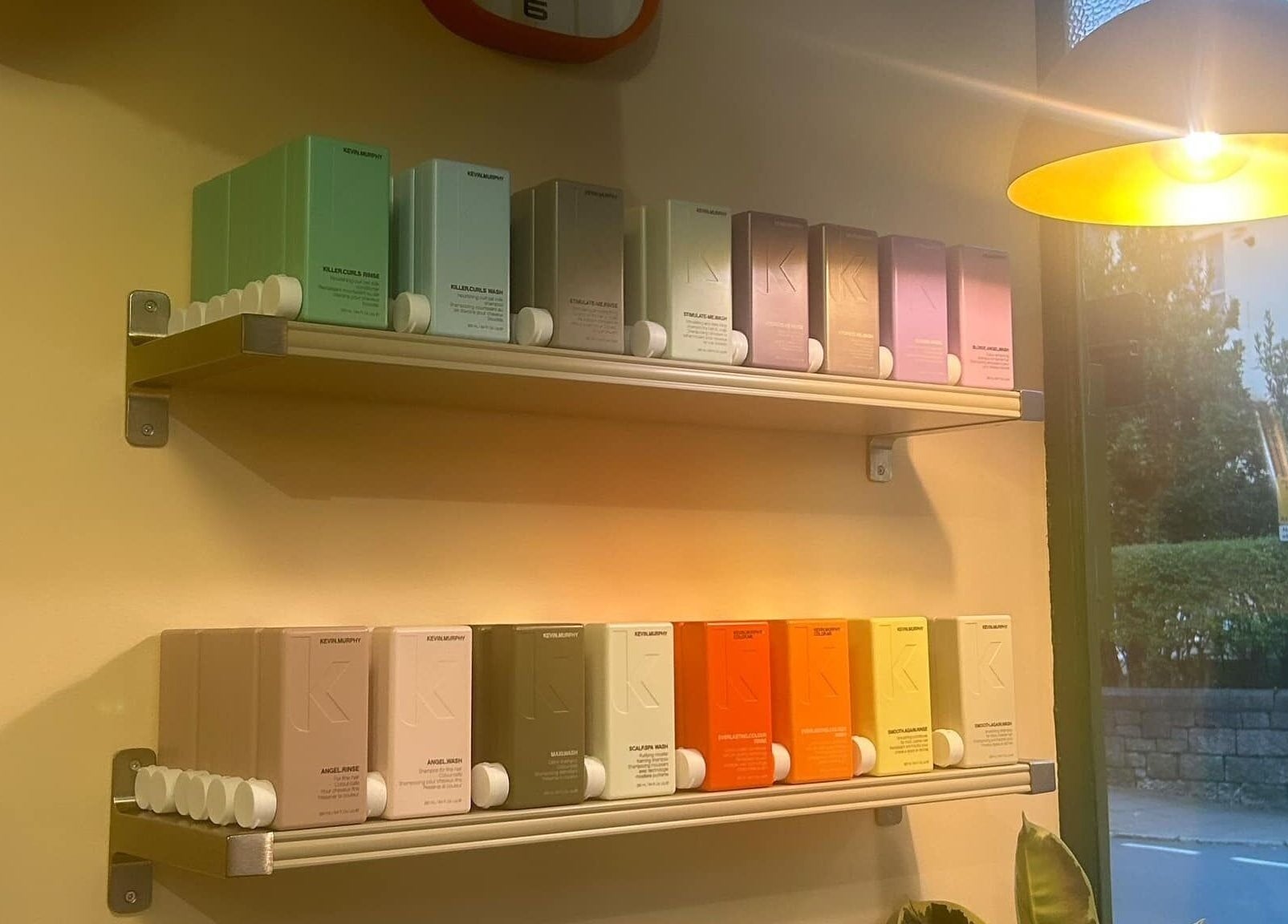 Vibrant hair products on shelves at Peach 37, Exeter, England, GB, illuminated by warm light.