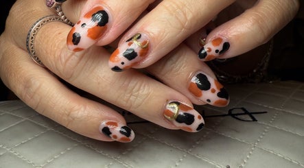 Stylish nail art at BySammieJo, Rainham, England, GB. Bold black and orange design on manicured hands.