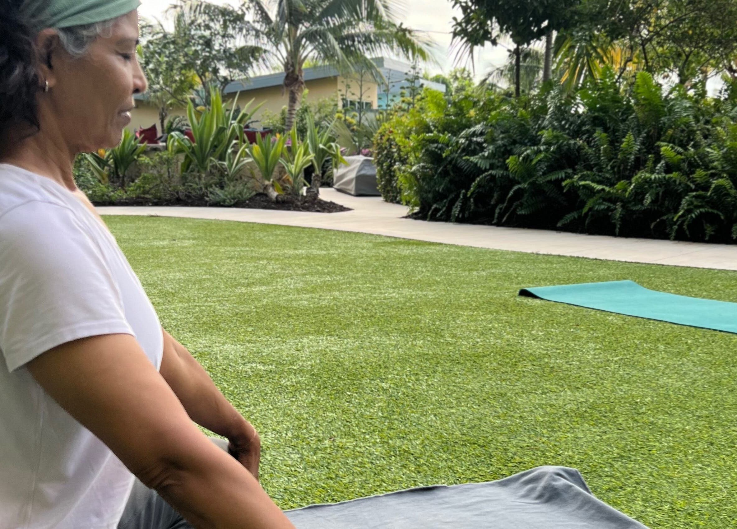 Outdoor yoga session at Breathe with Betty, Grand Cayman, KY, in a lush garden setting.