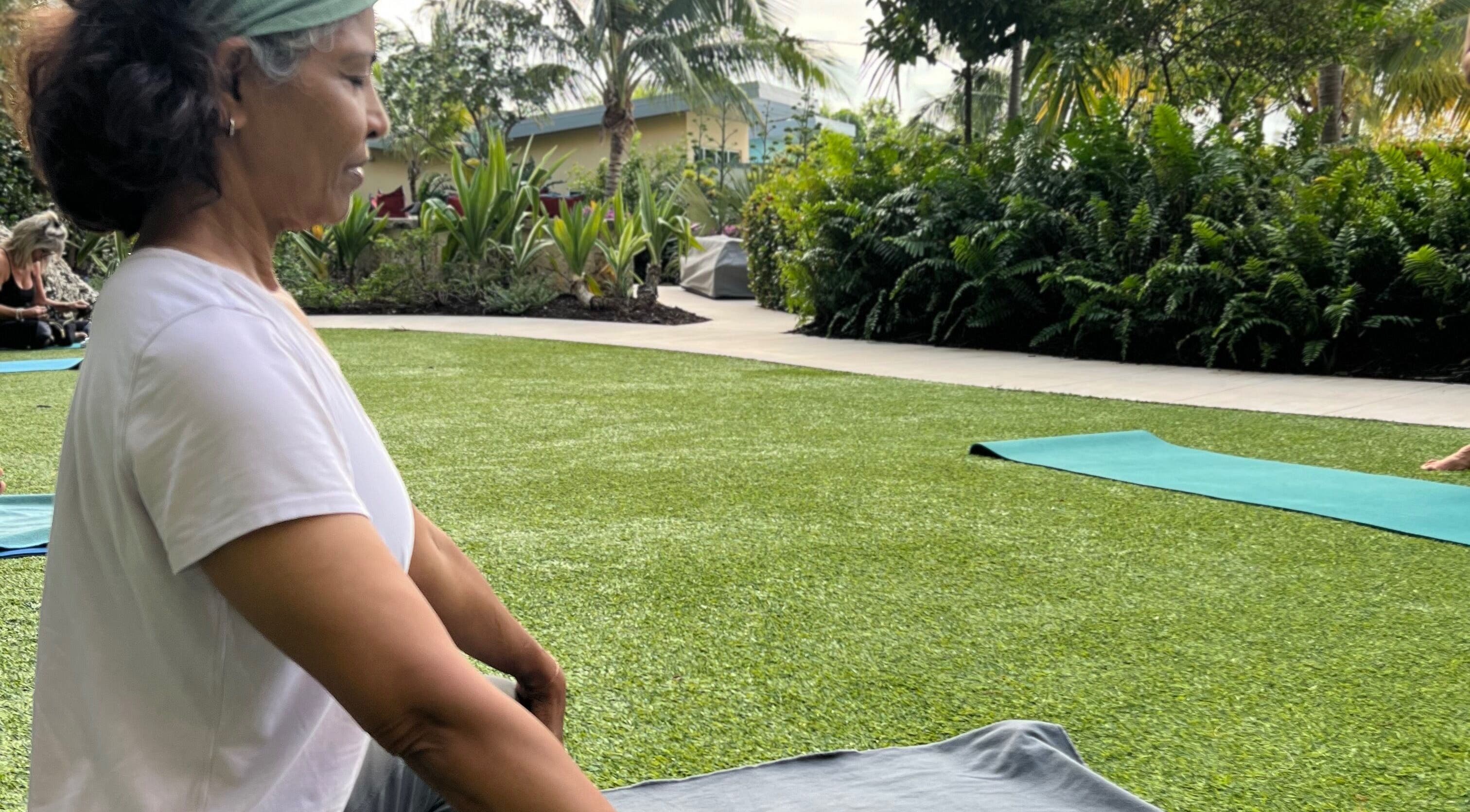 Outdoor yoga session at Breathe with Betty, Grand Cayman, KY, in a lush garden setting.