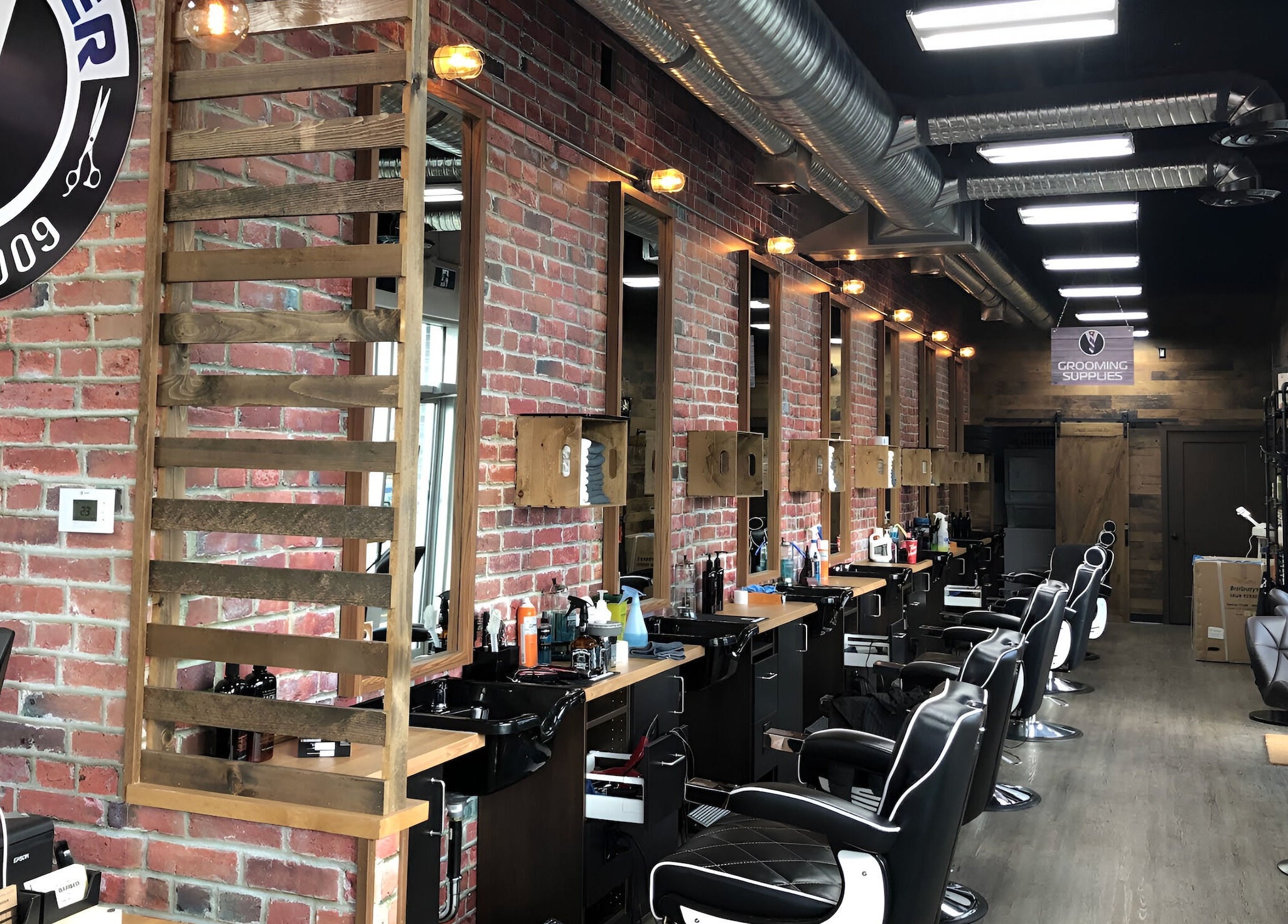 Interior of Mr. Barber St. Albert in Alberta, CA, showcasing rustic brick walls and sleek barber stations.