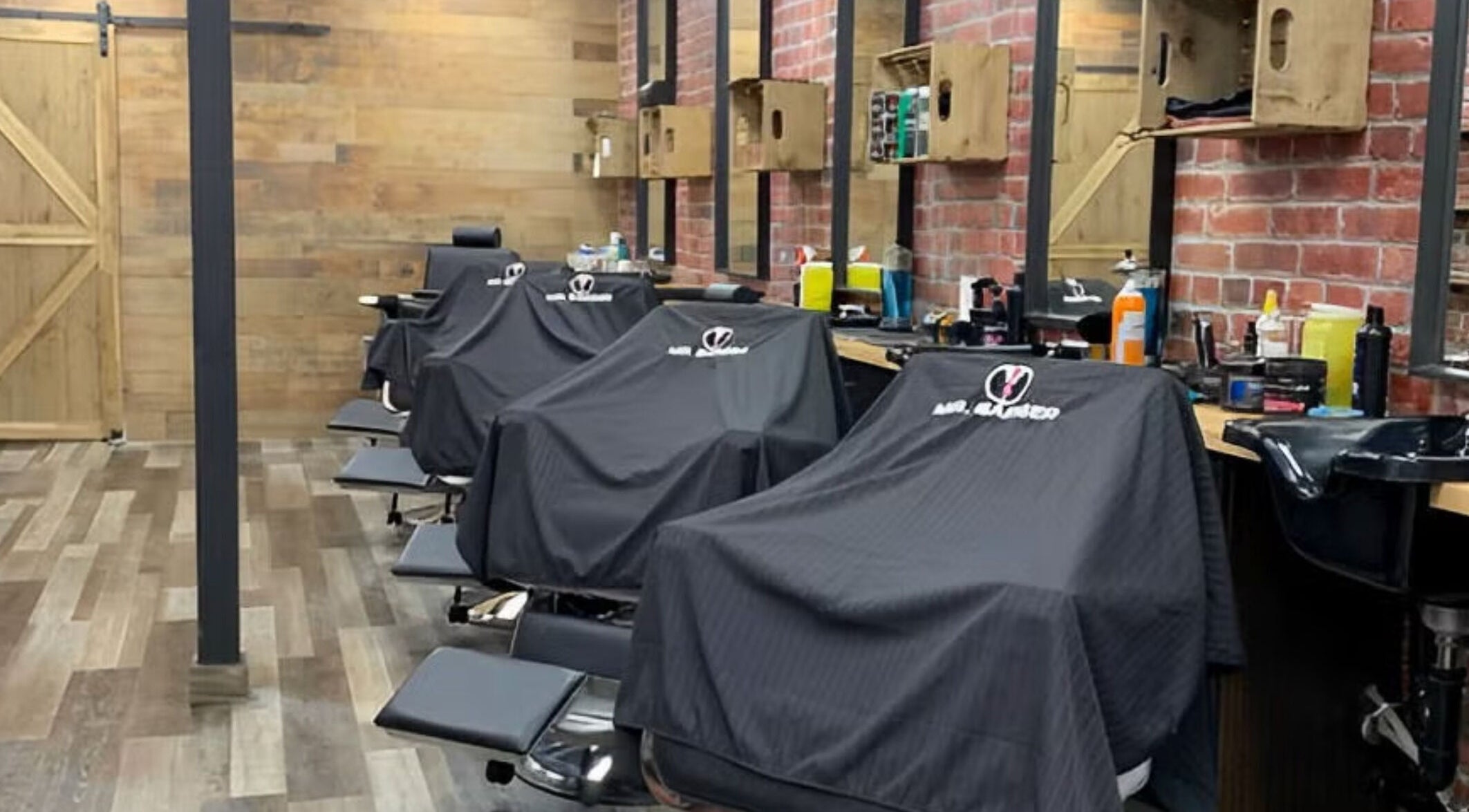 Interior view of Mr. Barber Hamptons, Edmonton, Alberta, CA with stylish barber chairs and exposed brick design.