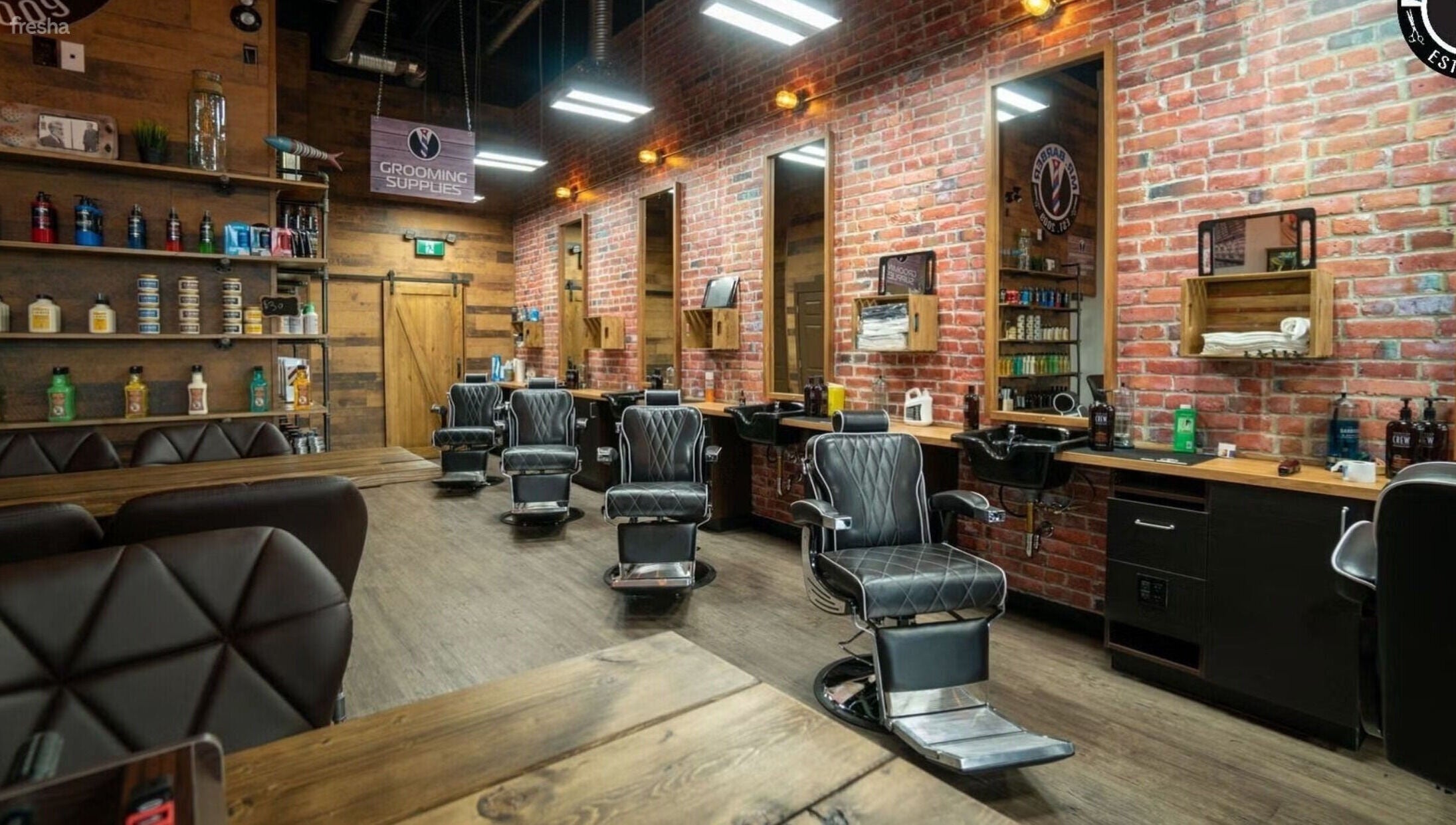 Interior of Mr. Barber - Millwoods Tipaskan, Edmonton, Alberta, CA featuring stylish chairs and brick walls.