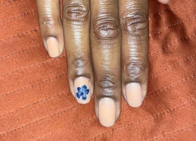 Manicure with floral accent nail by Nailphoria Beauty in Leeds, England, GB on orange fabric.