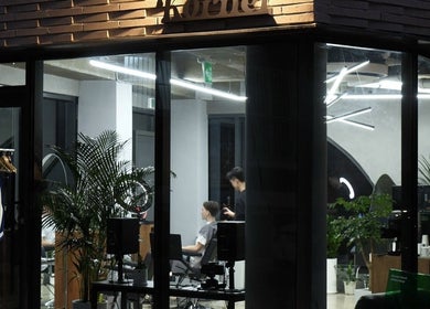 Korner Seoul salon view at night featuring modern interior and stylist with client. Seoul, 서울특별시, KR.