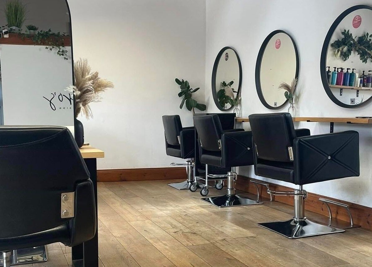 Modern salon interior at Bavaro, Aldwincle, England, GB with sleek black chairs and mirrors.