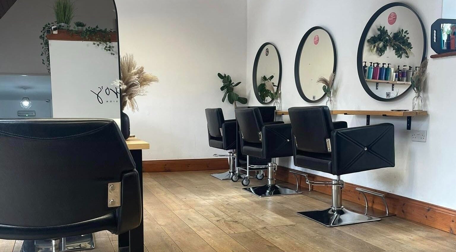Modern salon interior at Bavaro, Aldwincle, England, GB with sleek black chairs and mirrors.