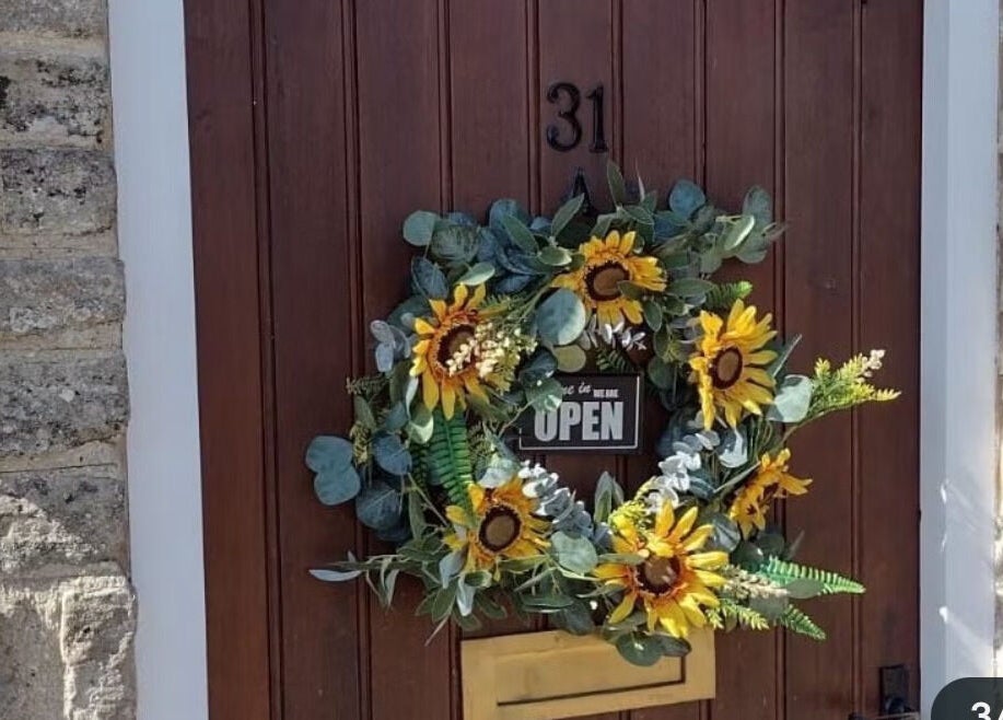 Sunflower wreath on Bavaro's wooden door, Aldwincle, England, GB welcoming guests.