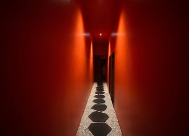 Dimly lit, serene red hallway with pebble pathway at Tê Spa, Đà Nẵng, Đà Nẵng, VN.