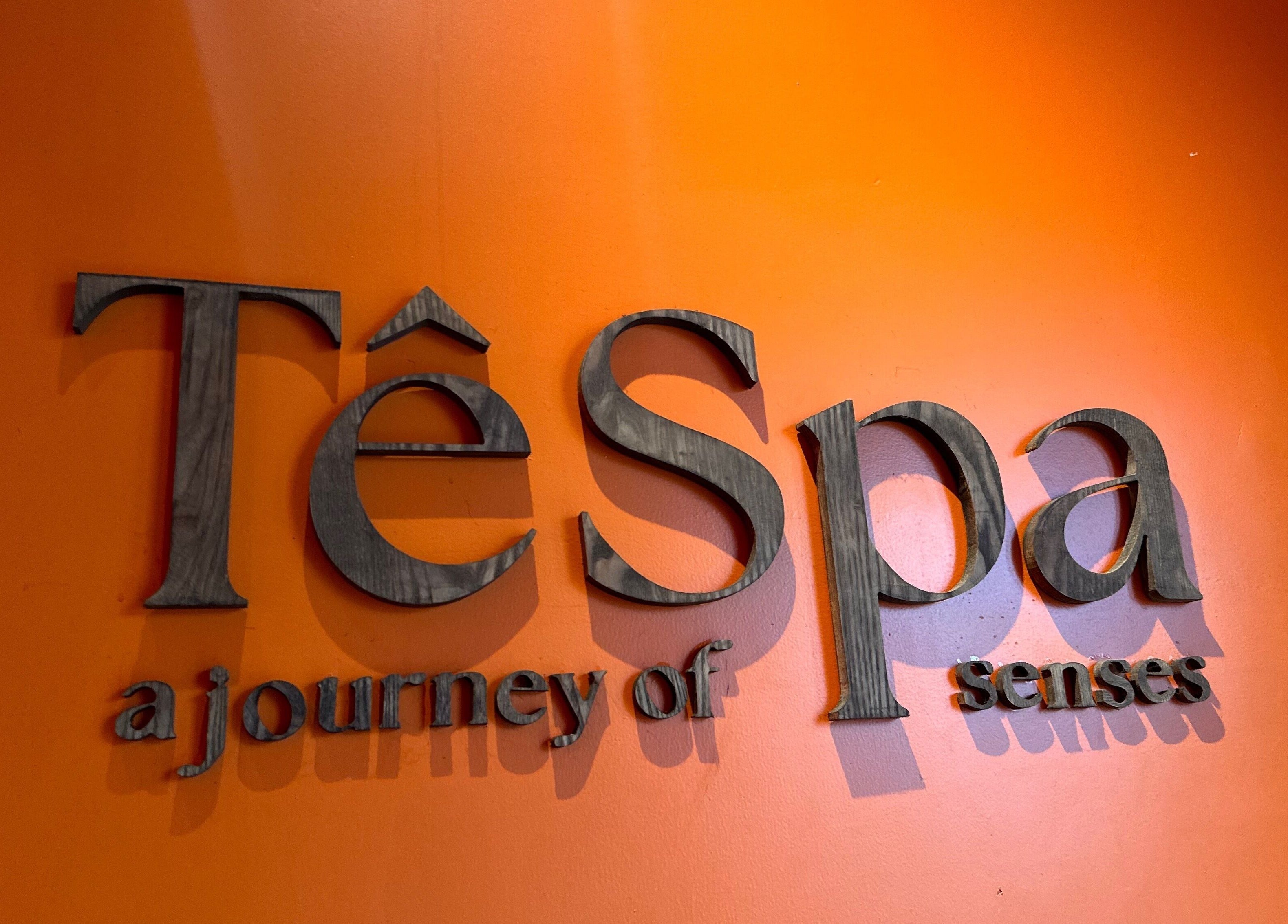 Tê Spa logo on vibrant orange wall in Đà Nẵng, Đà Nẵng, VN, highlighting journey of senses.