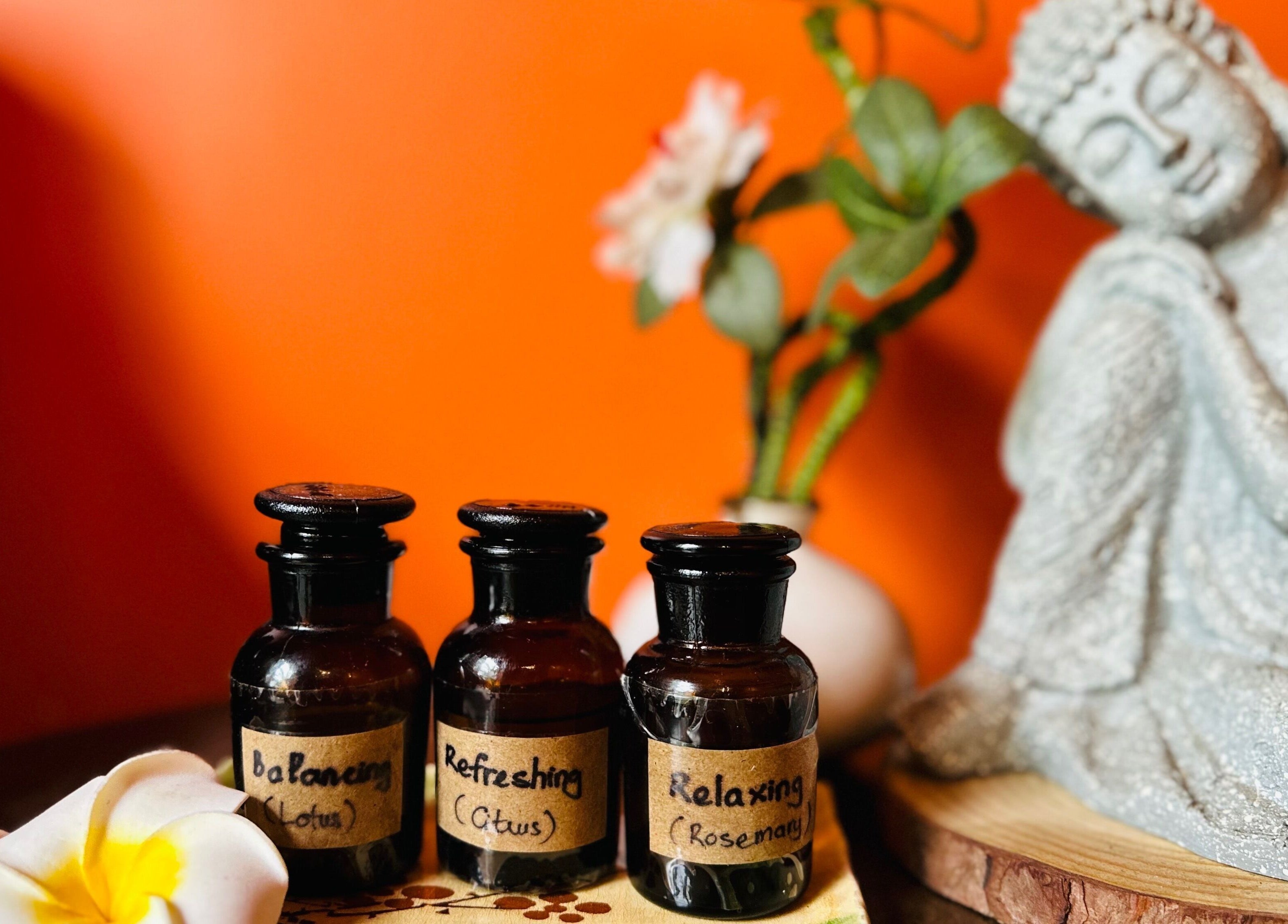 Aromatherapy oils at Tê Spa, Đà Nẵng, VN, enhancing relaxation with Buddha statue and plumeria decor.