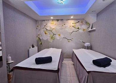 Tranquil massage room at Healthlan Massage & Spa, London, England, GB with orchid decor and twin tables.