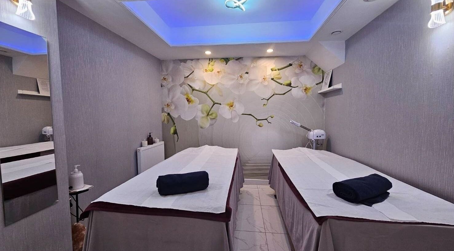 Tranquil massage room at Healthlan Massage & Spa, London, England, GB with orchid decor and twin tables.