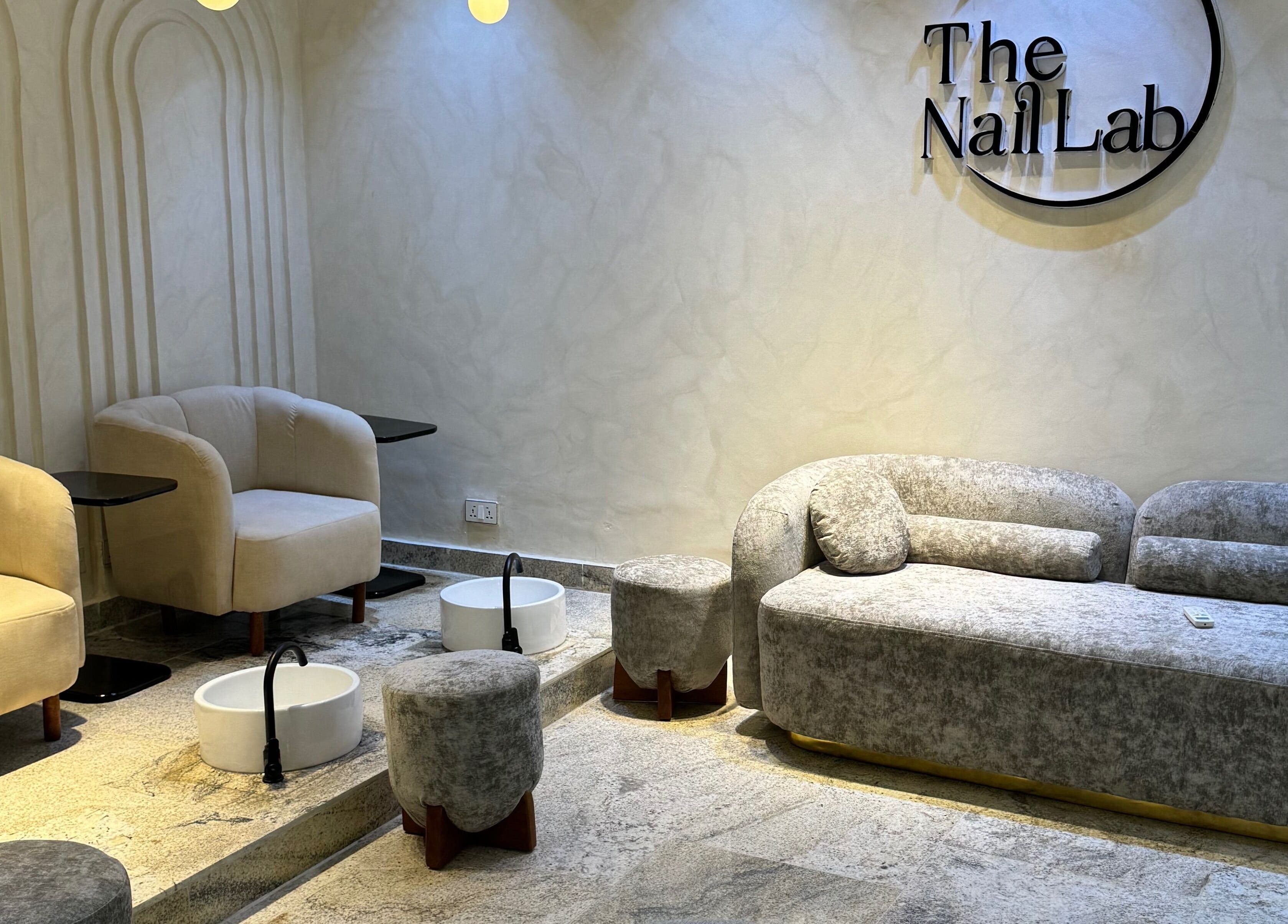 Relaxing seating area at The Nail Lab in Abuja, Federal Capital Territory, NG with plush chairs and foot basins.