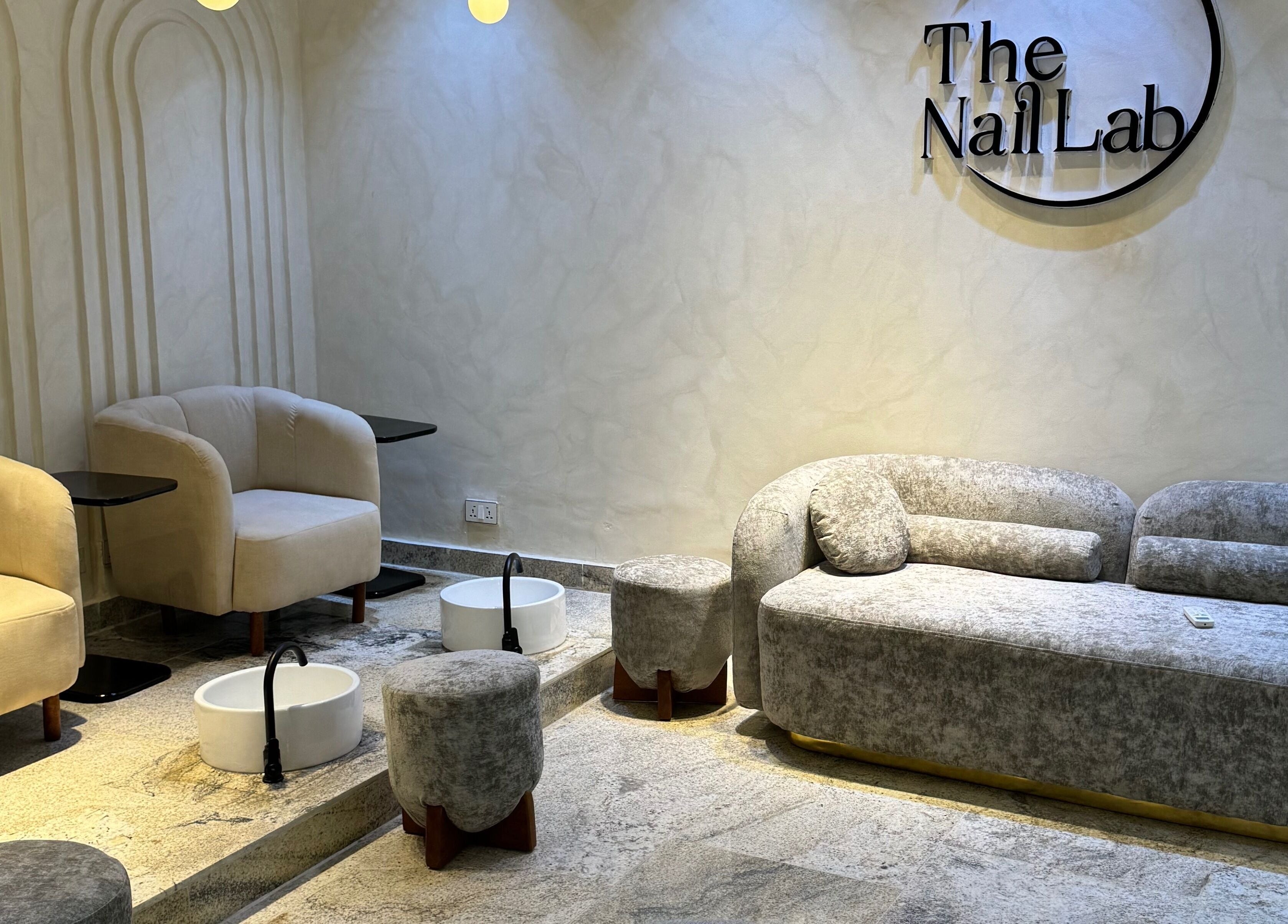Relaxing seating area at The Nail Lab in Abuja, Federal Capital Territory, NG with plush chairs and foot basins.