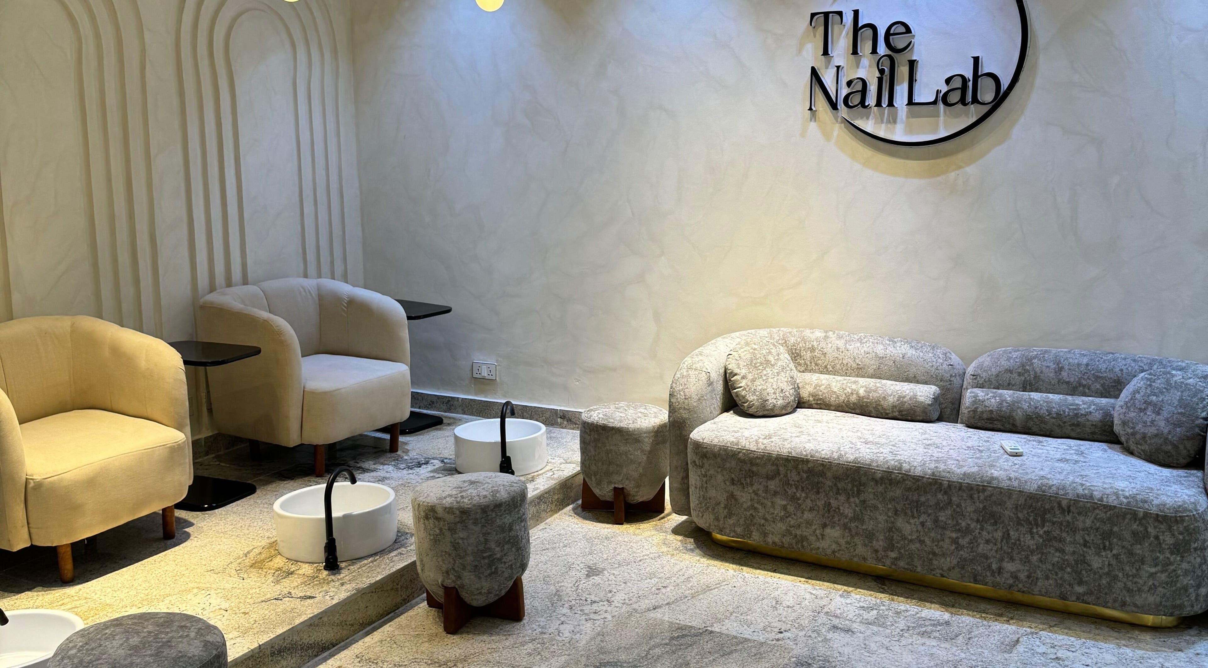 Relaxing seating area at The Nail Lab in Abuja, Federal Capital Territory, NG with plush chairs and foot basins.
