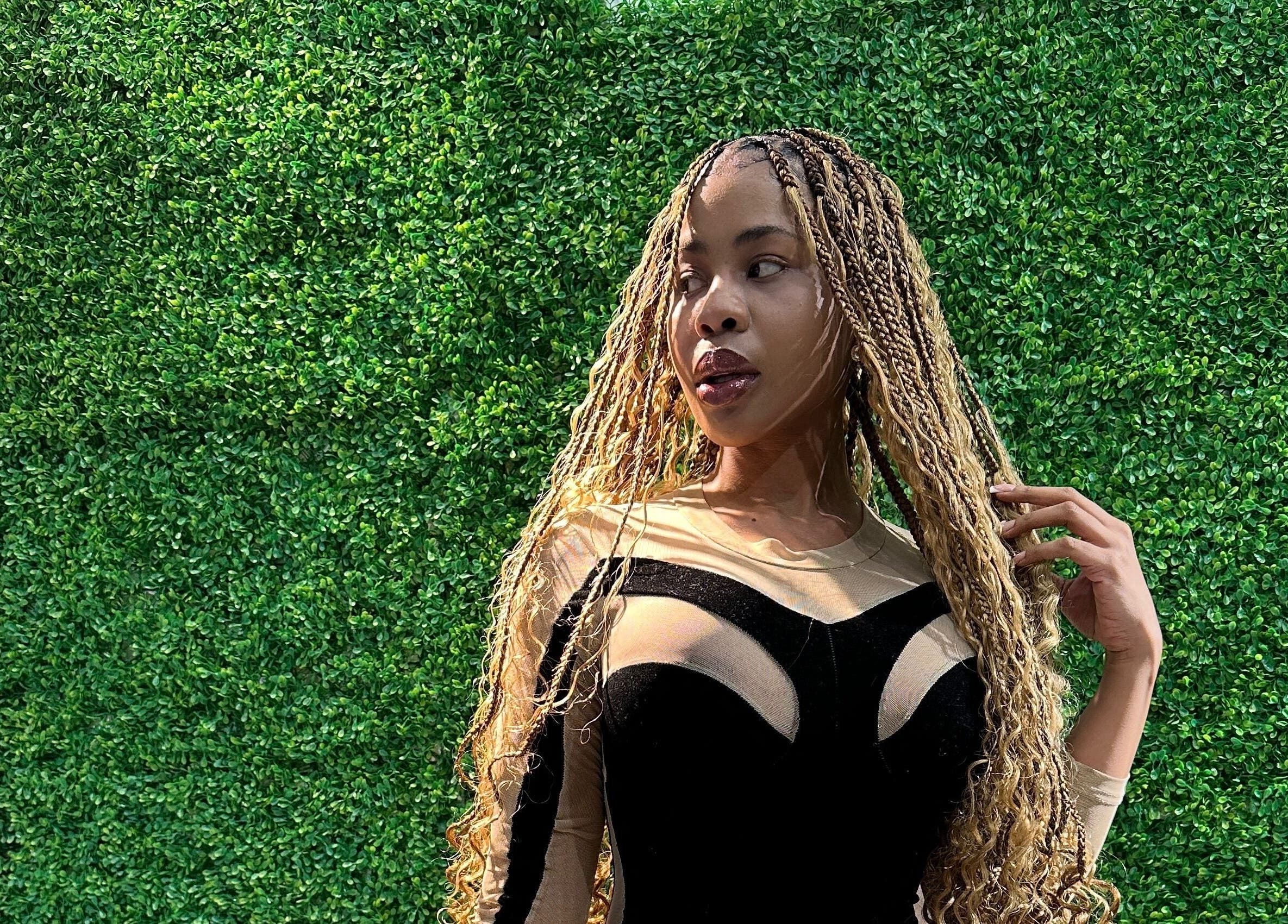 Model in stylish attire at Freeman Beauty Palace, Johannesburg, Gauteng, ZA, against a lush green wall.