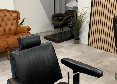 Interno di Verve Men Salon a Selargius, Sardegna, IT, con poltrona moderna e divano vintage.