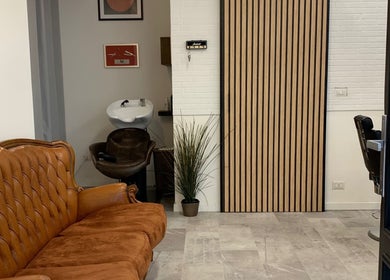 Interno accogliente di Verve Men Salon, Selargius, Sardegna, IT con divano in pelle e lavandino moderno.