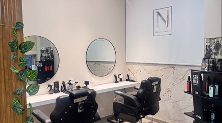 Κομψός χώρος κουρέματος στο NJ HAIR & NAILS SALON, Νέα Σμύρνη, GR. Δύο μαύρες καρέκλες μπροστά από καθρέφτες.